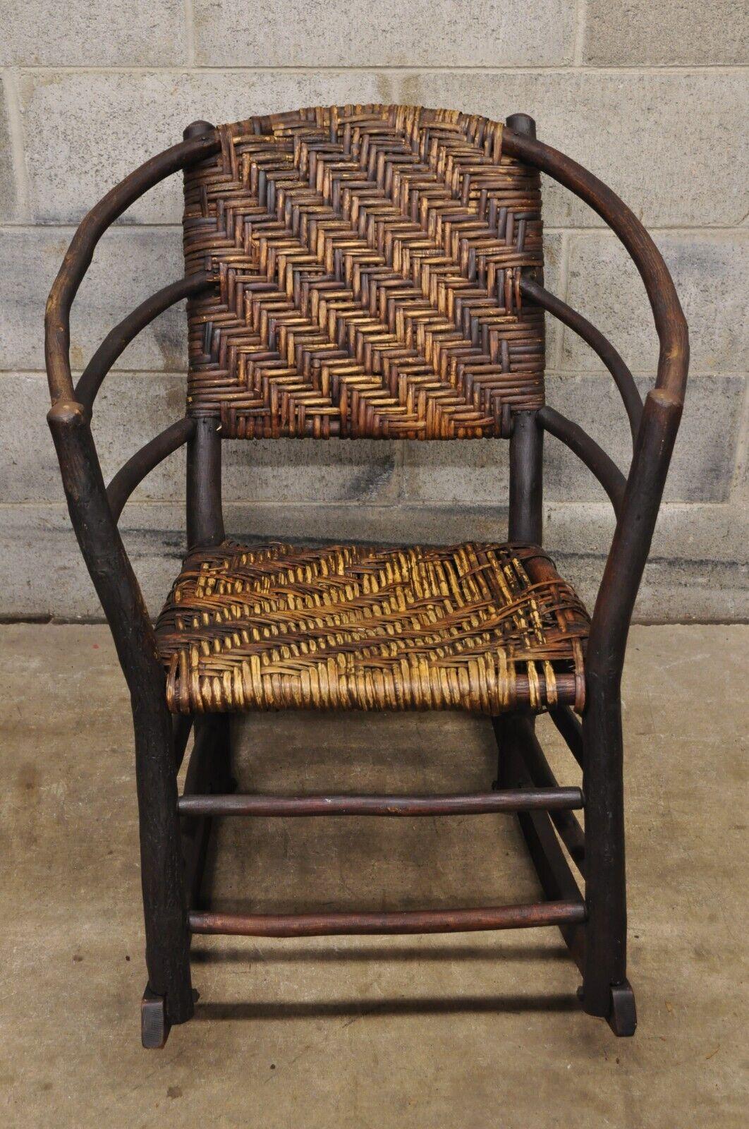 Vieille chaise à bascule Adirondack en rotin avec cadre en bois et branches d'arbre, style vieux hickory. Le dossier et l'assise sont en rotin tressé, le cadre est large, la construction en bois massif, la finition est vieillie, c'est un très bel