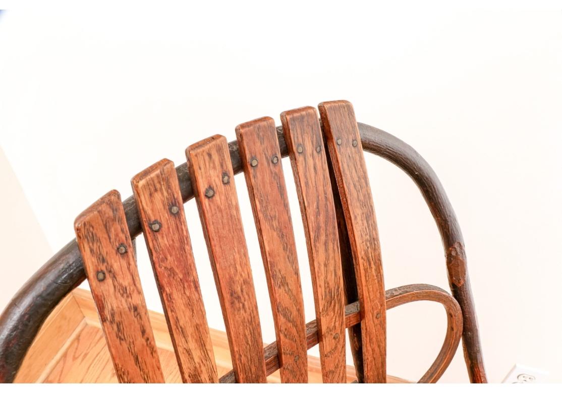 Dondolo in stile Adirondack del XX secolo in quercia e hickory curvato con chiodi a vista, schienale a traliccio e a volute, struttura solida con una bella patina.

Dimensioni: L. 23 1/2