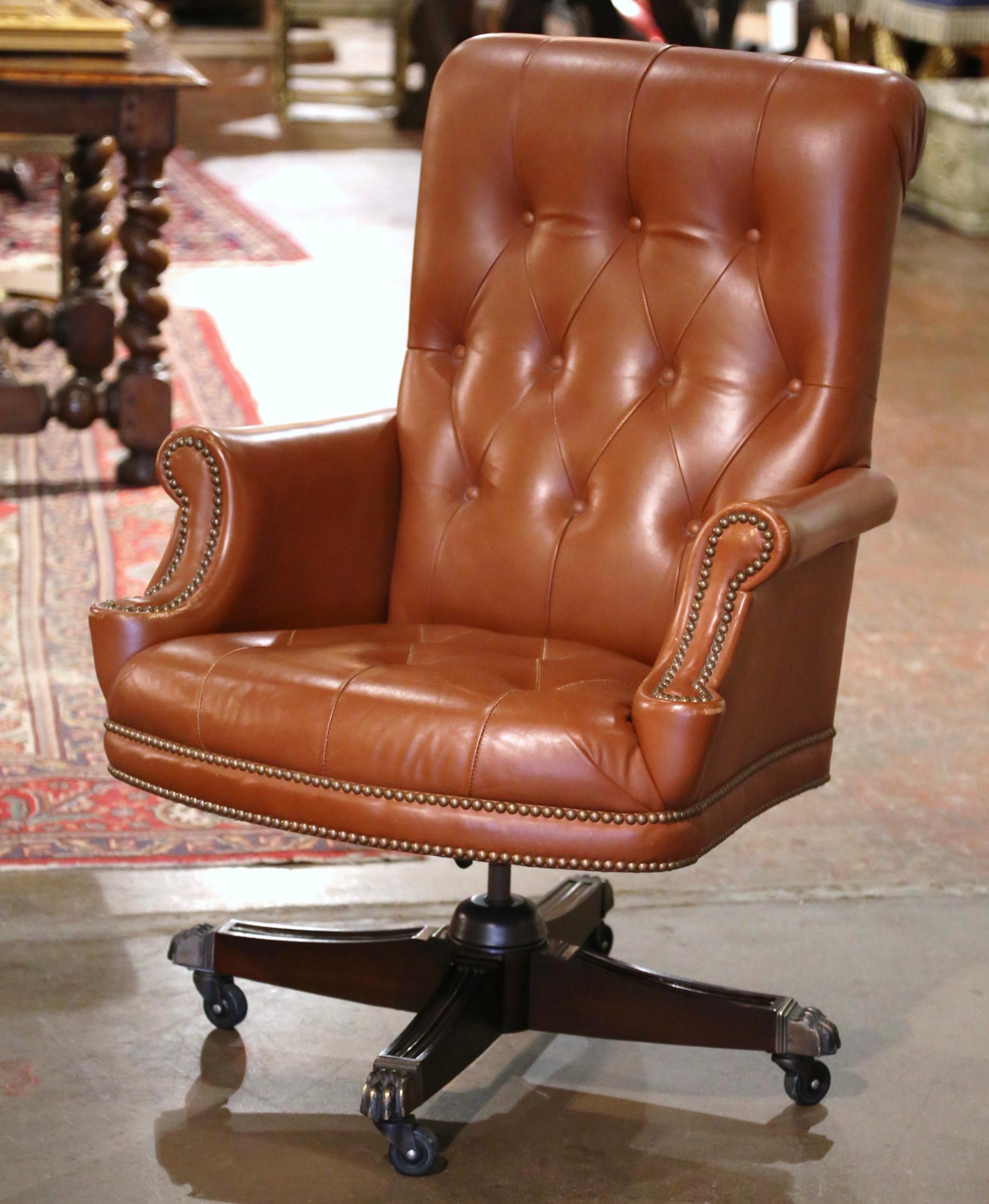 Dress a man's office or study with this elegant vintage armchair. Hand crafted circa 1980 in the Chesterfield style, the chair stands on a swivel base with wooden legs ending in gilt metal casters. The tall chair with rolled arms, rolled back is