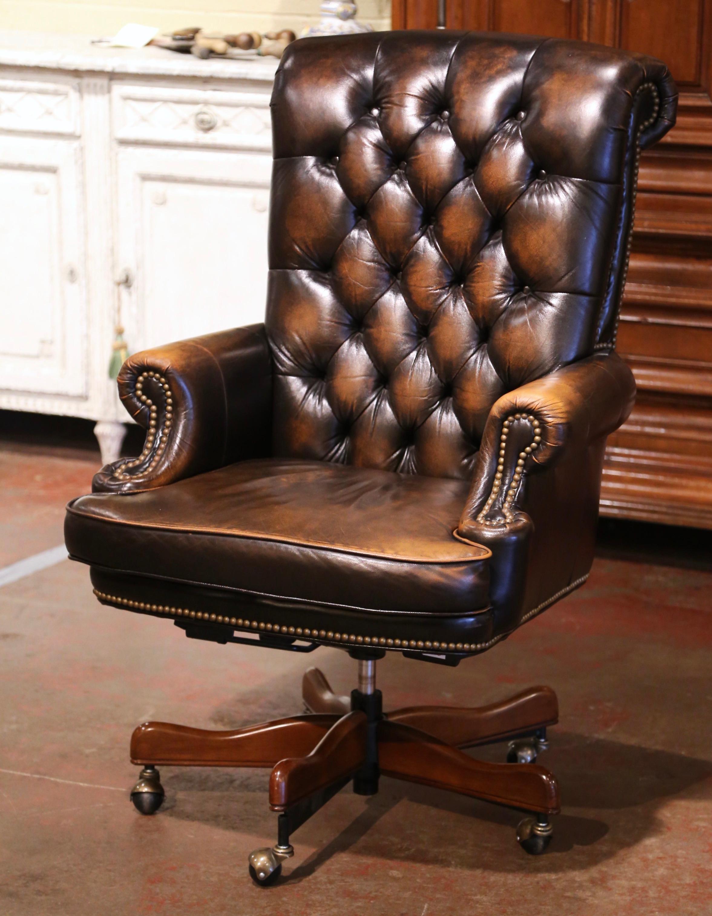 Dress a man's office or study with this elegant vintage armchair. Hand crafted circa 1980 in the Chesterfield style, the chair stands on a swivel base with wooden legs ending in gilt metal casters. The tall chair with rolled arms, rolled back and