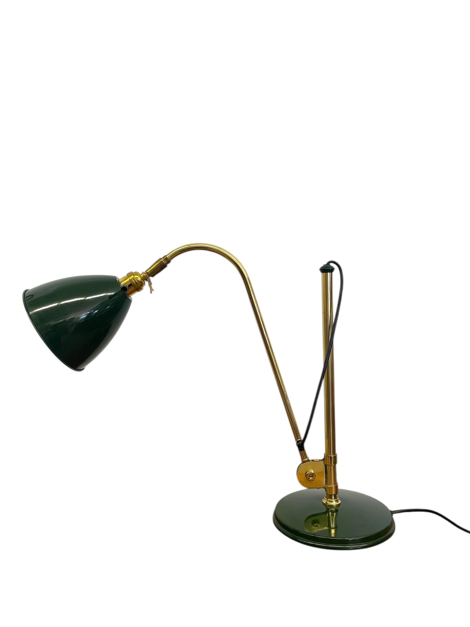 Cette lampe de bureau vintage combine une élégante construction en laiton avec une riche finition en émail vert foncé, offrant à la fois style et fonctionnalité. La lampe est dotée d'un support vertical réglable avec une articulation pivotante à la