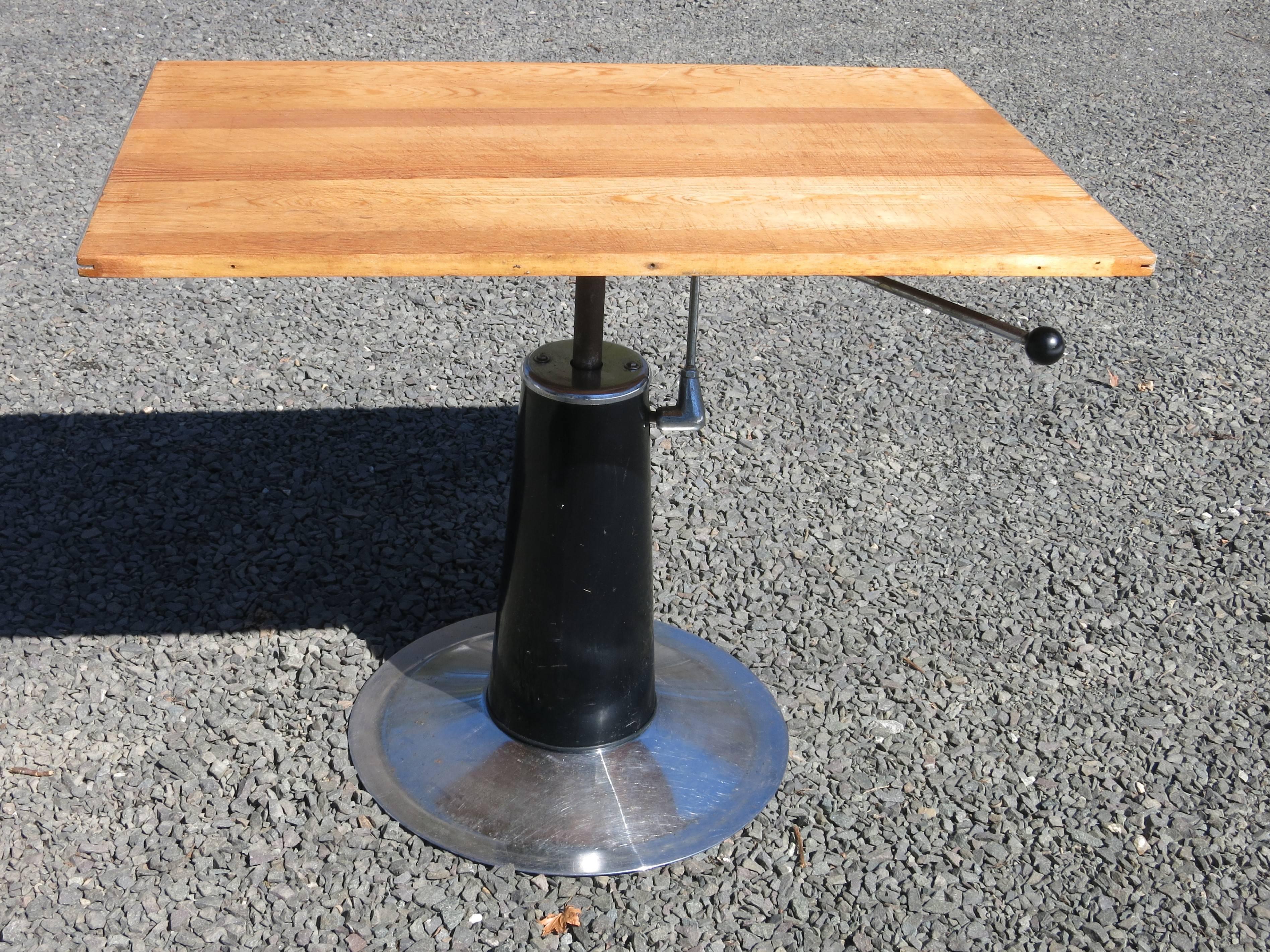 Vintage adjustable hydraulic drafting work table in the Nike of Eskilstun style. Item features a hydraulic lift height adjustment, swivel and tilt top with locking mechanism, and a round metal pedestal base with black metal central column. Top has