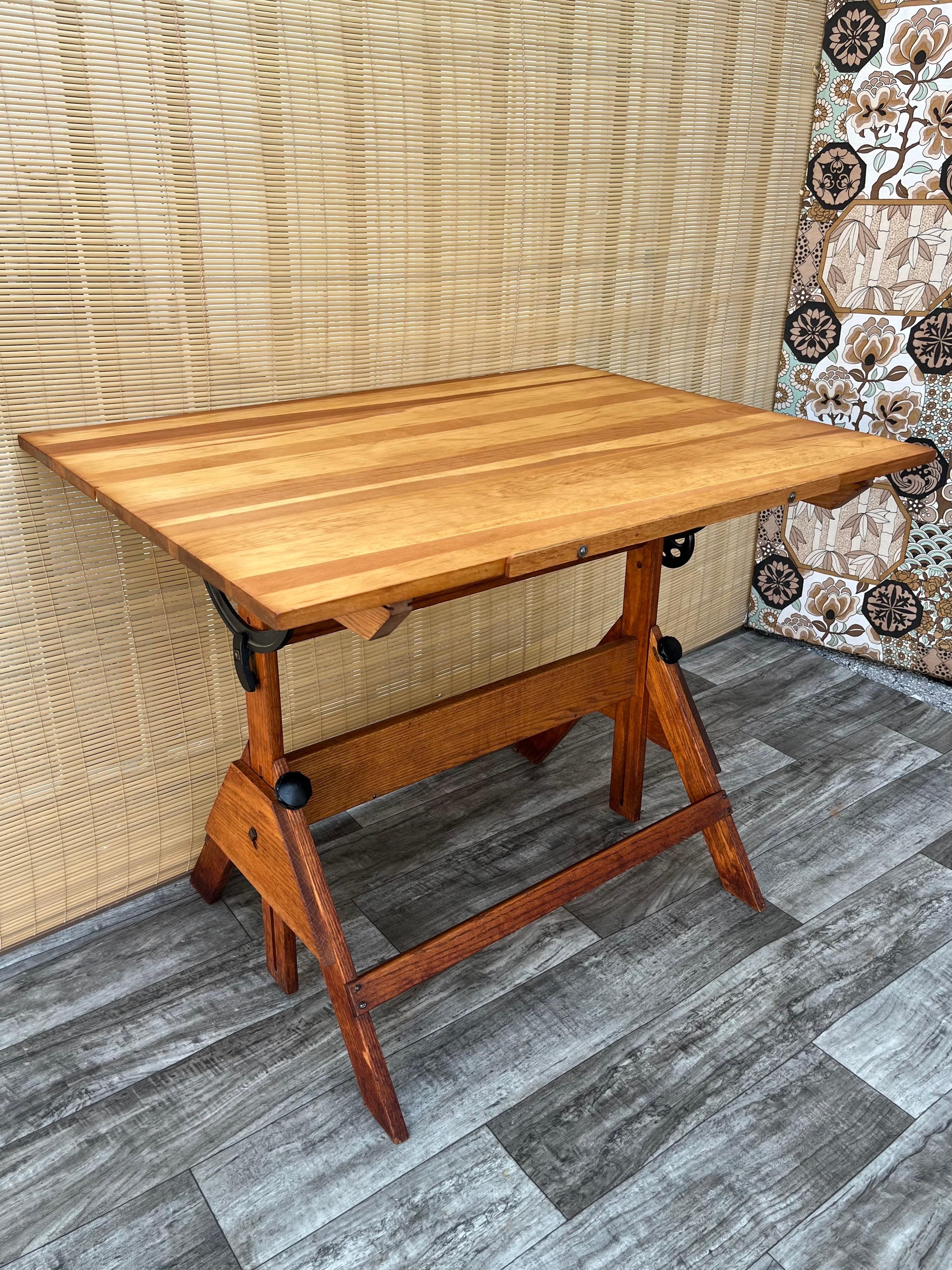 Vintage adjustable height Industrial drafting table. circa 1960s.
Features and adjustable height and tilting drawing / working surface, cast iron hardware, solid wood frame, and a working surface with beautiful natural wood grain.
The top tilts on