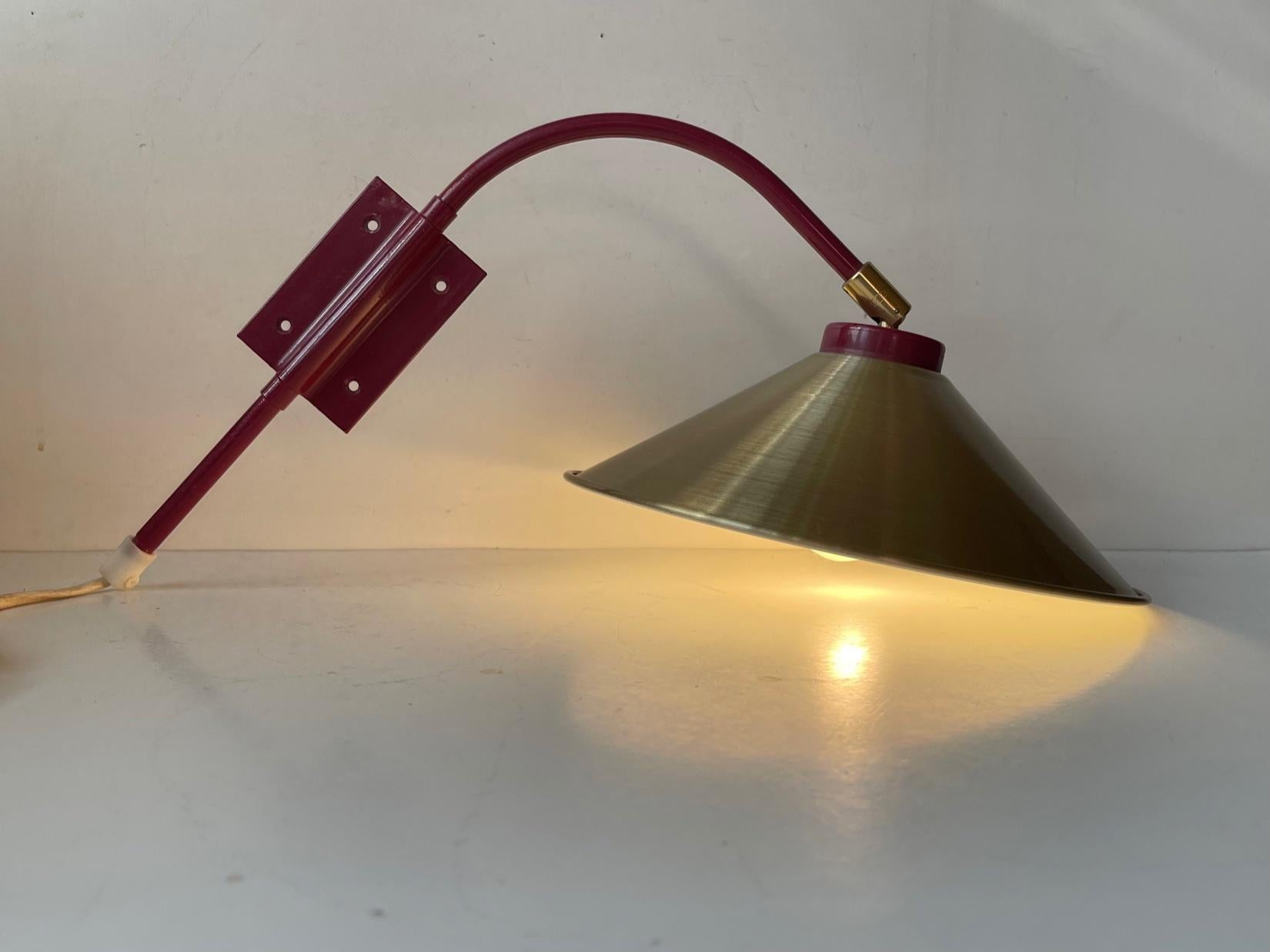 Adjustable wine red metal wall light with brass details and a brass alloy shade. It would make a great reading light. It can be adjusted from side to side and up/down at the shade. Anonymous scandinavian maker circa 1980. Measurements: H: 32, D: 24,