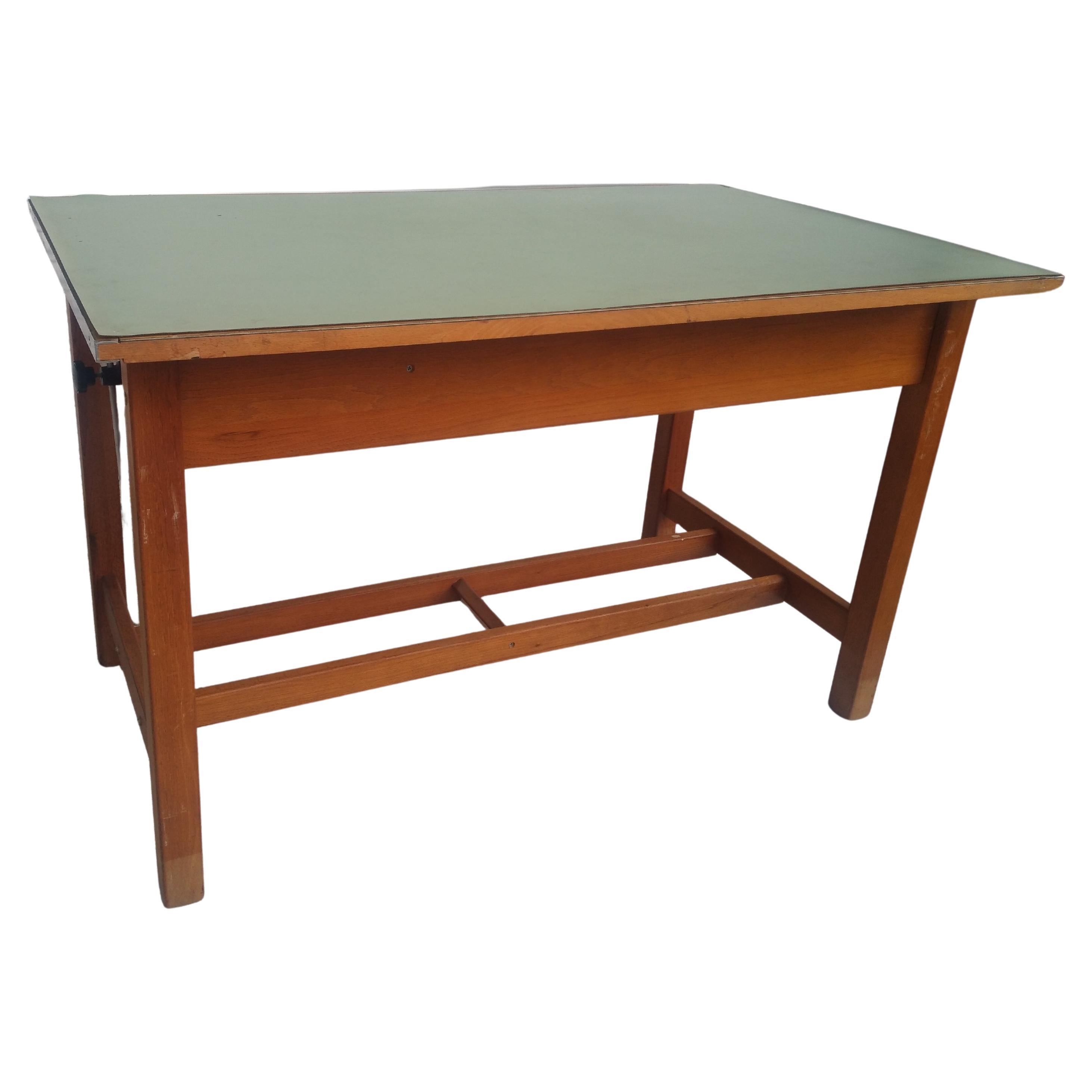 This is a vintage drafting table from the early 20th century. It's made of solid oak and has through tenons. The top can be replaced with new matting and the top adjust by the controlling arms on the side. It also has a foot rest and 2 drawers. One