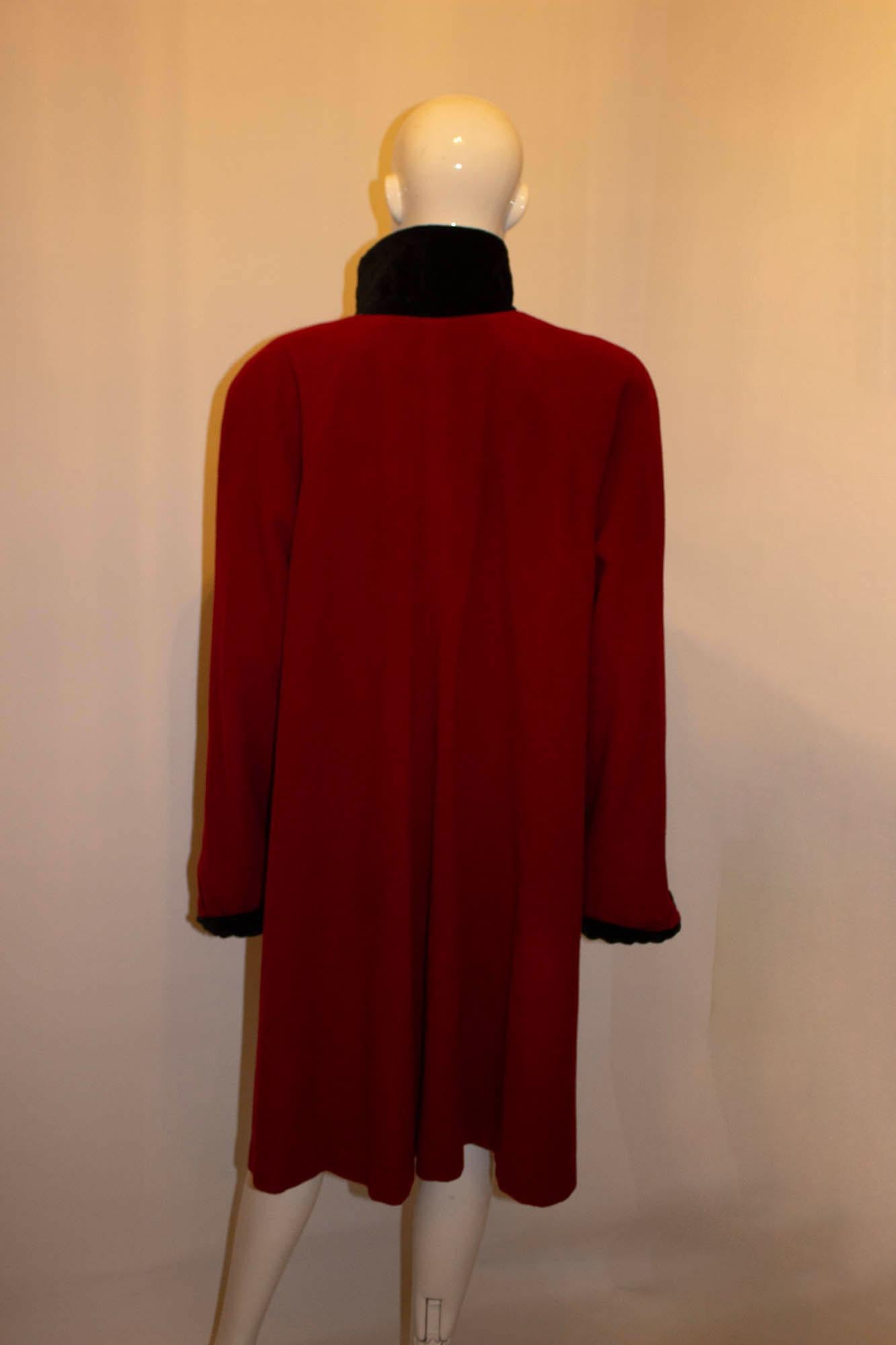 A great coat for winter weather, by Admyra for Selfridges. In a great shade of red, the coat has a black velvet collar and cuffs , and black velvet button opening. It is loose fitting with a pocket on either side,. Size 14 petite, measurements :