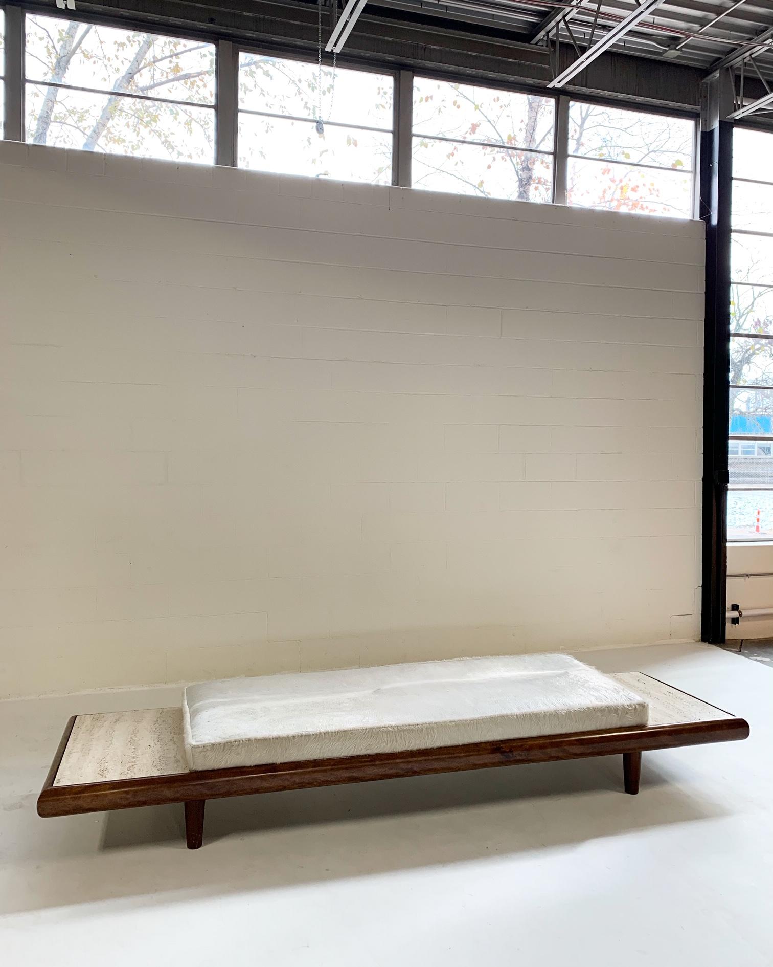 Vintage Adrian Pearsall style walnut and travertine daybed sofa with custom Brazilian ivory cowhide cushion.

We love the look of this daybed. The walnut frame, the travertine marble details. For its restoration, our designers chose the