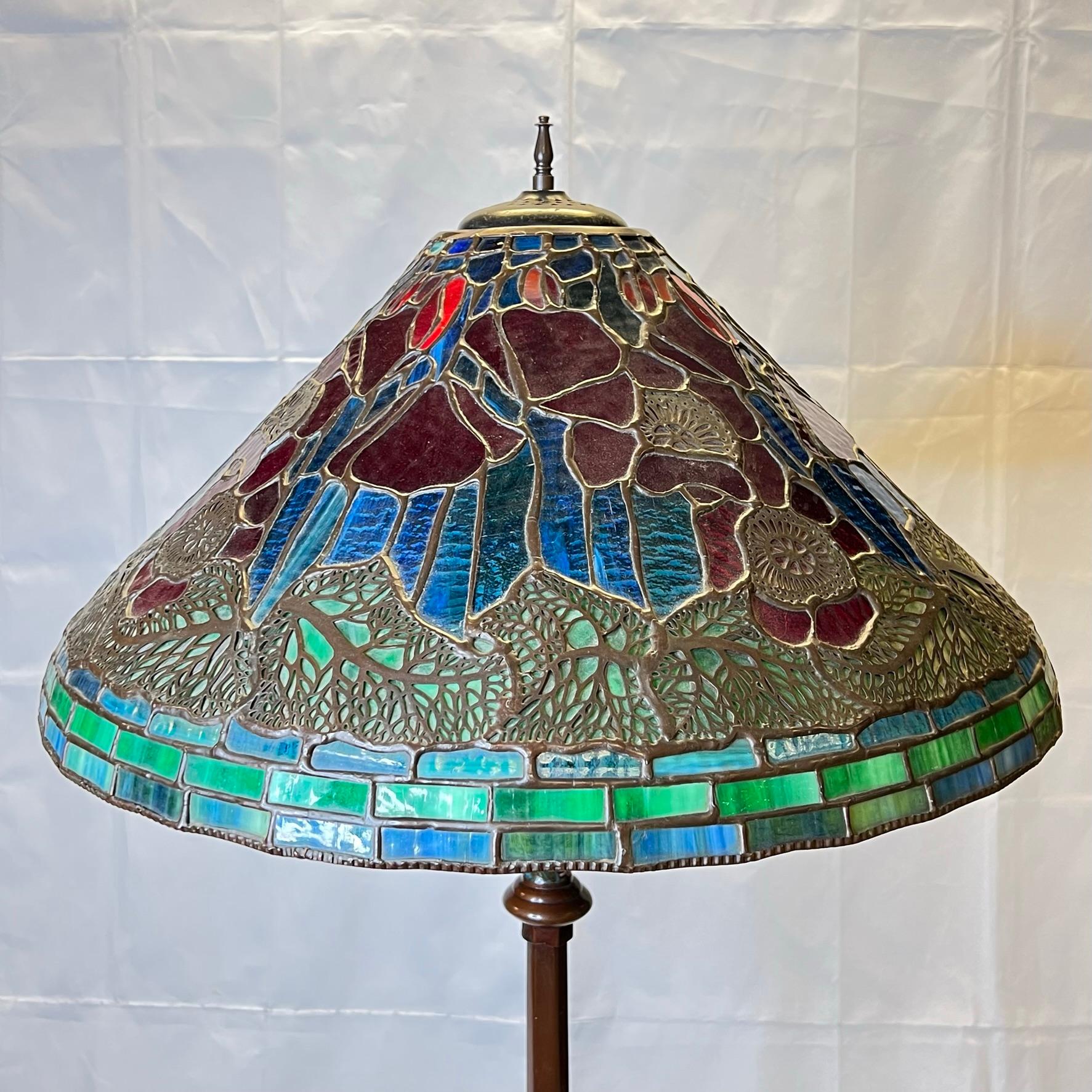 Lampada da terra vintage con base in bronzo intarsiato con smalto a campione e paralume in vetro piombato con disegni floreali multicolore.  Con presa, cavo e spina funzionanti, pronto per l'uso.
