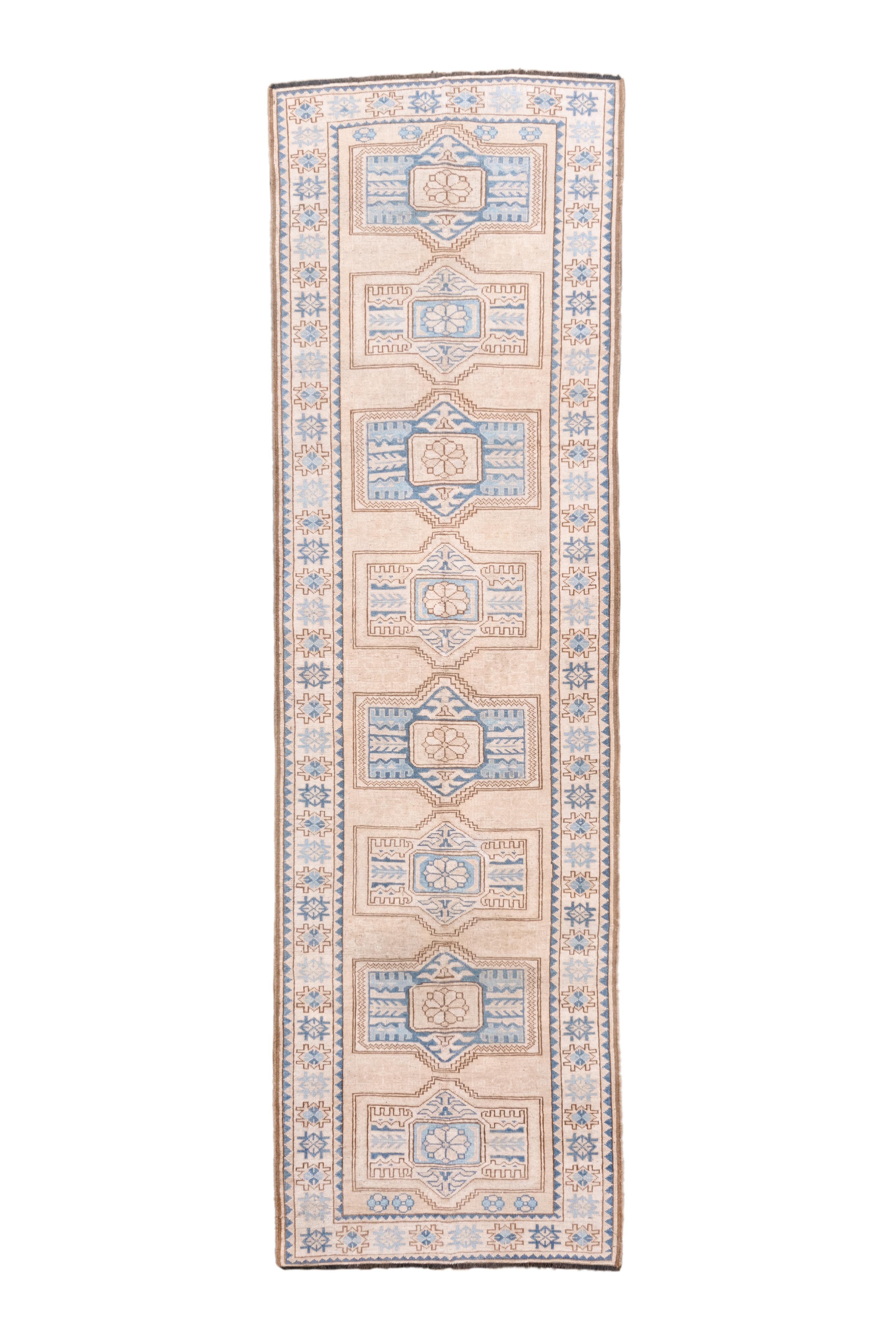 This kenare (runner) is an example of recent Afghan work, here in a Caucasian/Northwest Persian geometric style with eight cartouches aligned on a straw field. Touches of royal blue, cream and light-medium brown. Cream border with floating lozenges