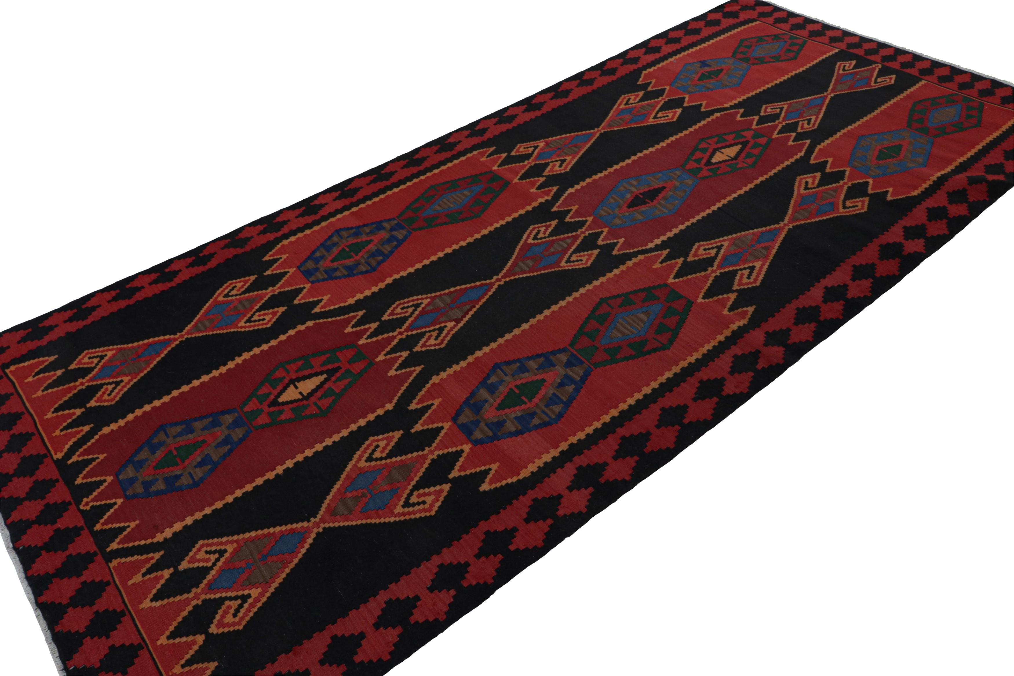 Handwoven in wool, circa 1950-1960, this 5x12 vintage Afghan tribal kilim rug features a minimal palette of rich red and blue with a black field. 

On the design: 

As an exciting curation in the Rug & Kilim Collection, this rug is a very personal