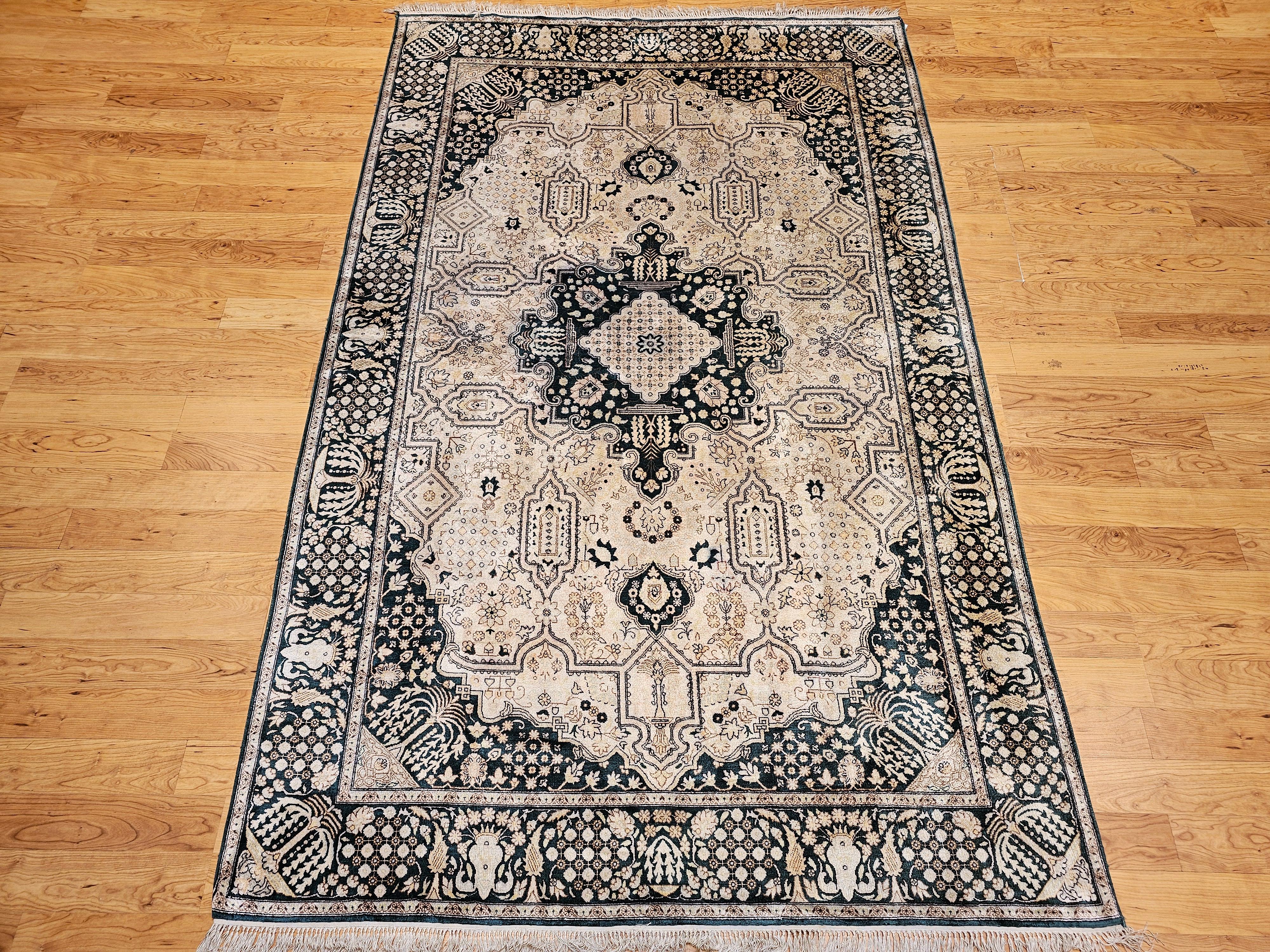 Vintage hand-knotted all silk rug with a silk pile on a silk foundation circa the 4th quarter of the 1900s in a dark green and ivory colors.  The rug is in a geometric medallion pattern with an ivory/cream color background and border in dark green. 