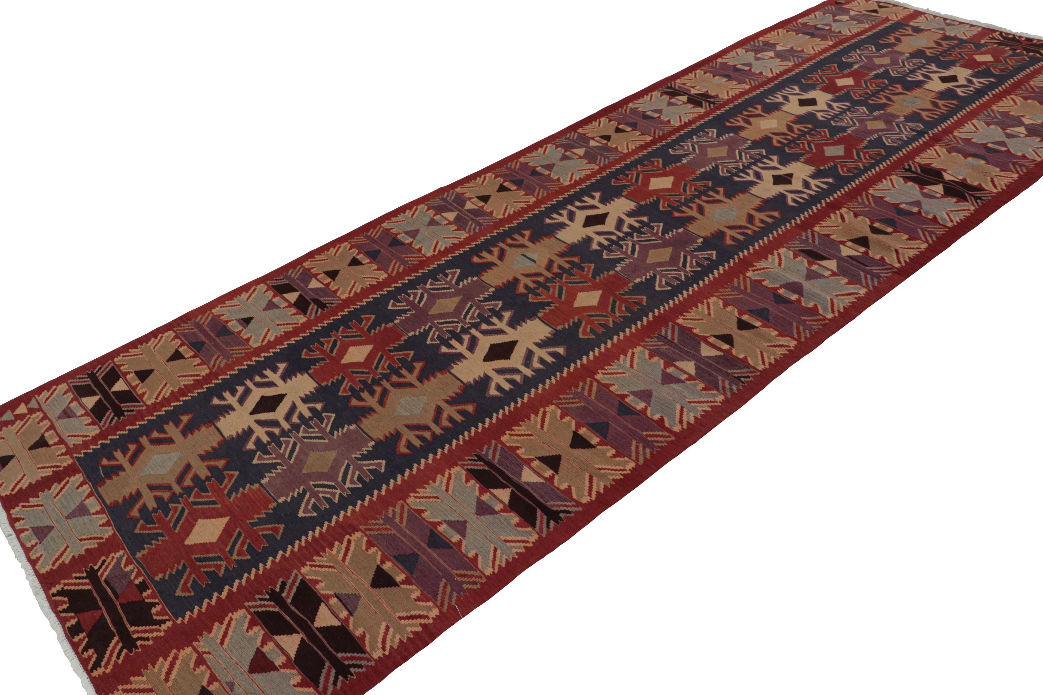 Handwoven in wool, circa 1950-1960, this 5x13 vintage Afghan tribal kilim and gallery runner rug, with geometric patterns in purple and beige/brown, features a deep blue field, and a red border. 

On the design: 

Featuring intricate geometric