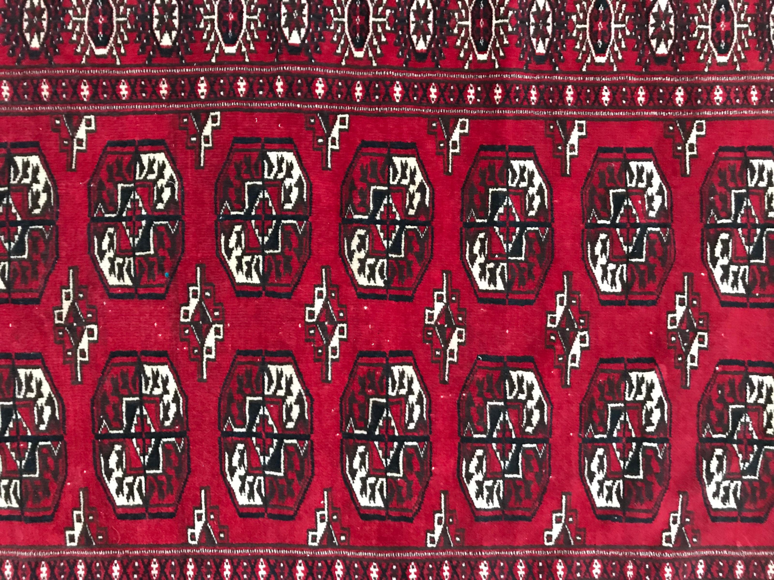Beau tapis turkmène d'Afghanistan du 20ème siècle, avec un joli motif géométrique et tribal Bokhara et des couleurs rouge et noir, entièrement noué à la main avec du velours de laine sur des fondations en laine.