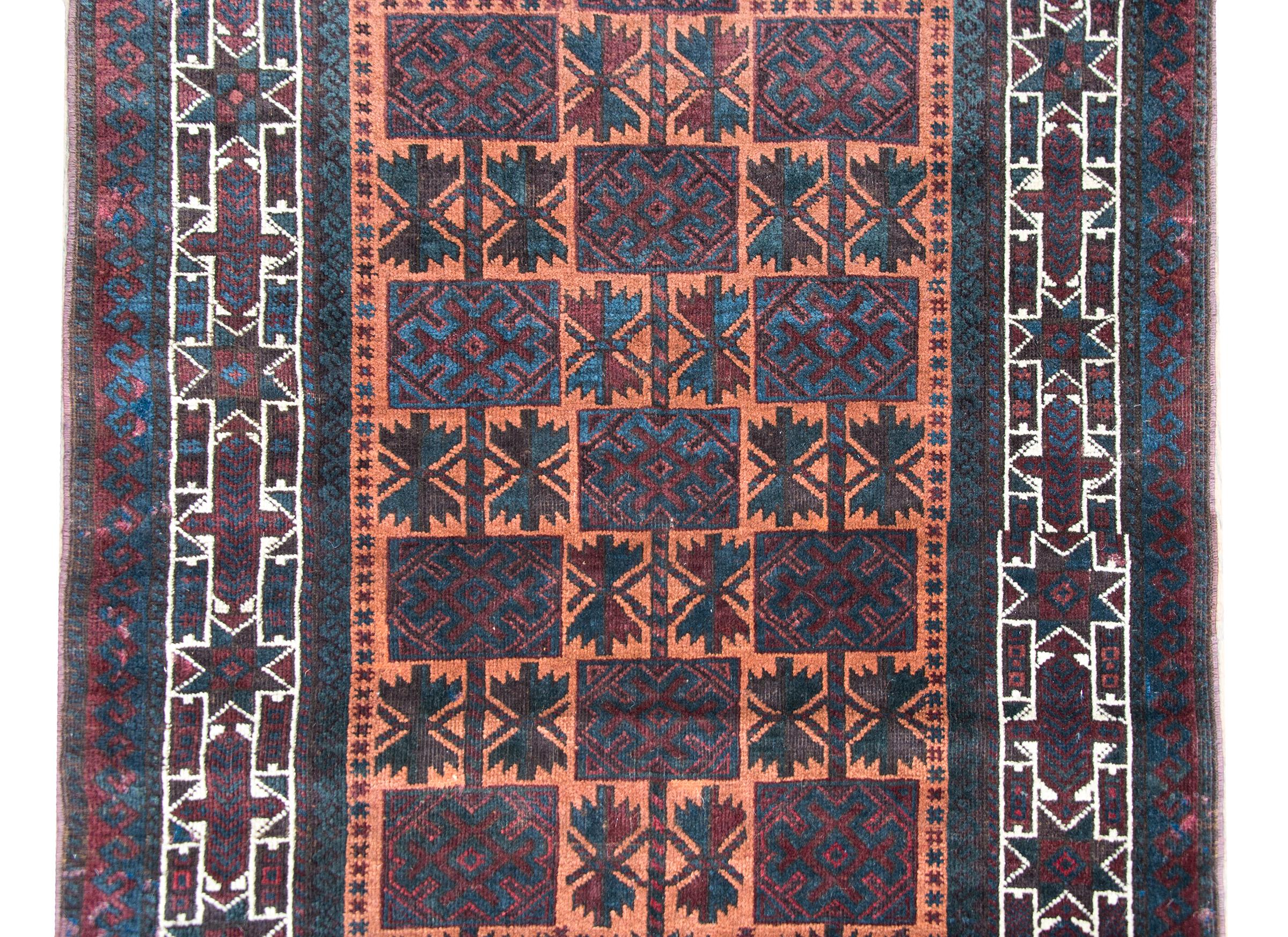 A wonderful mid-20th century Afghani prayer rug with a beautiful all-over stylized floral pattern arranged into a grid, and surrounded by even more stylized flowers, and all woven in muted reds, indigos, oranges, and white wool.