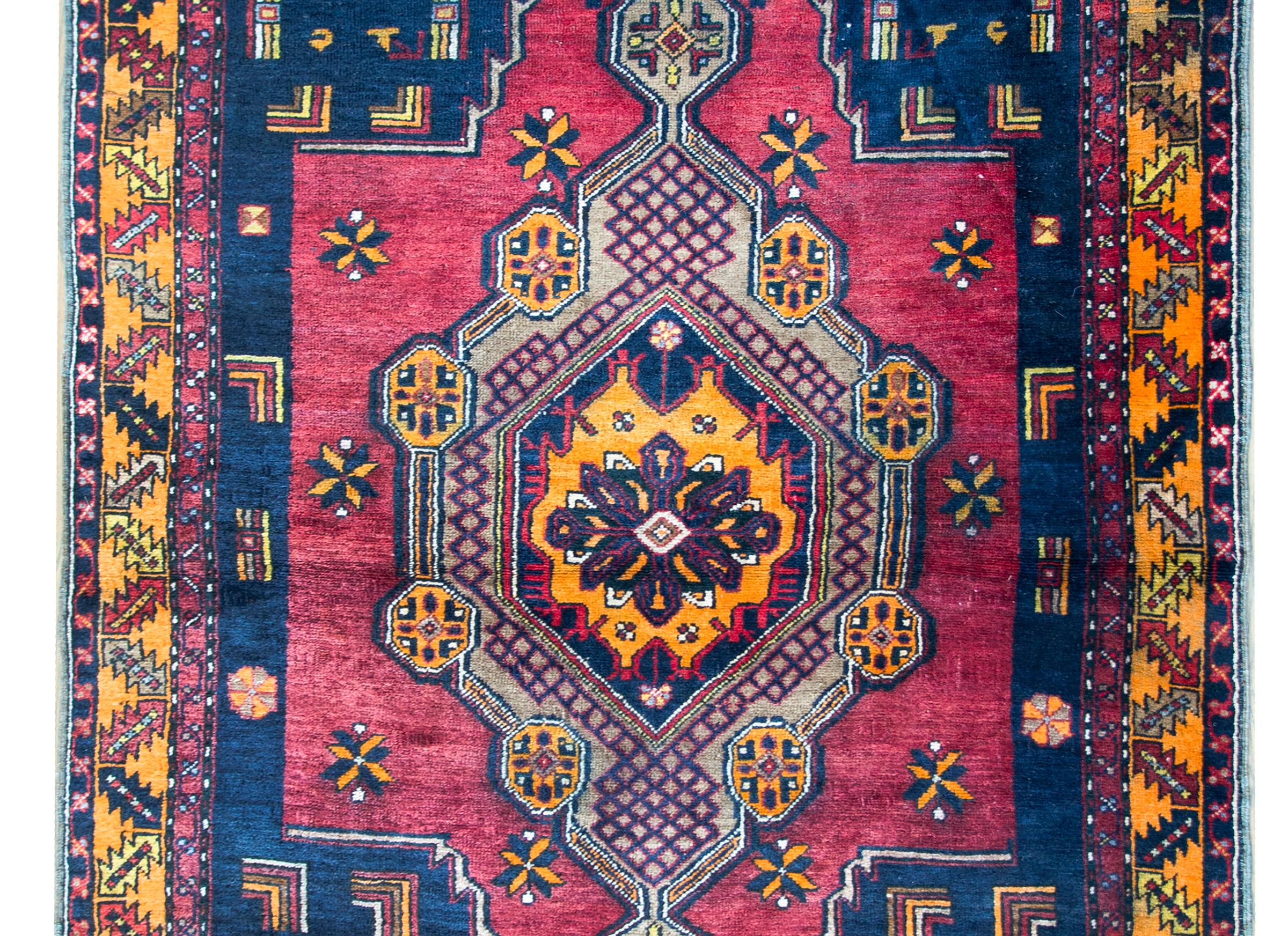 A beautiful mid-20th century Afghani Baluch rug with tribal pattern consisting of a large central floral medallion circled by another diamond medallion with more stylized floral motifs, and living amidst a field of geometric designs. The border is