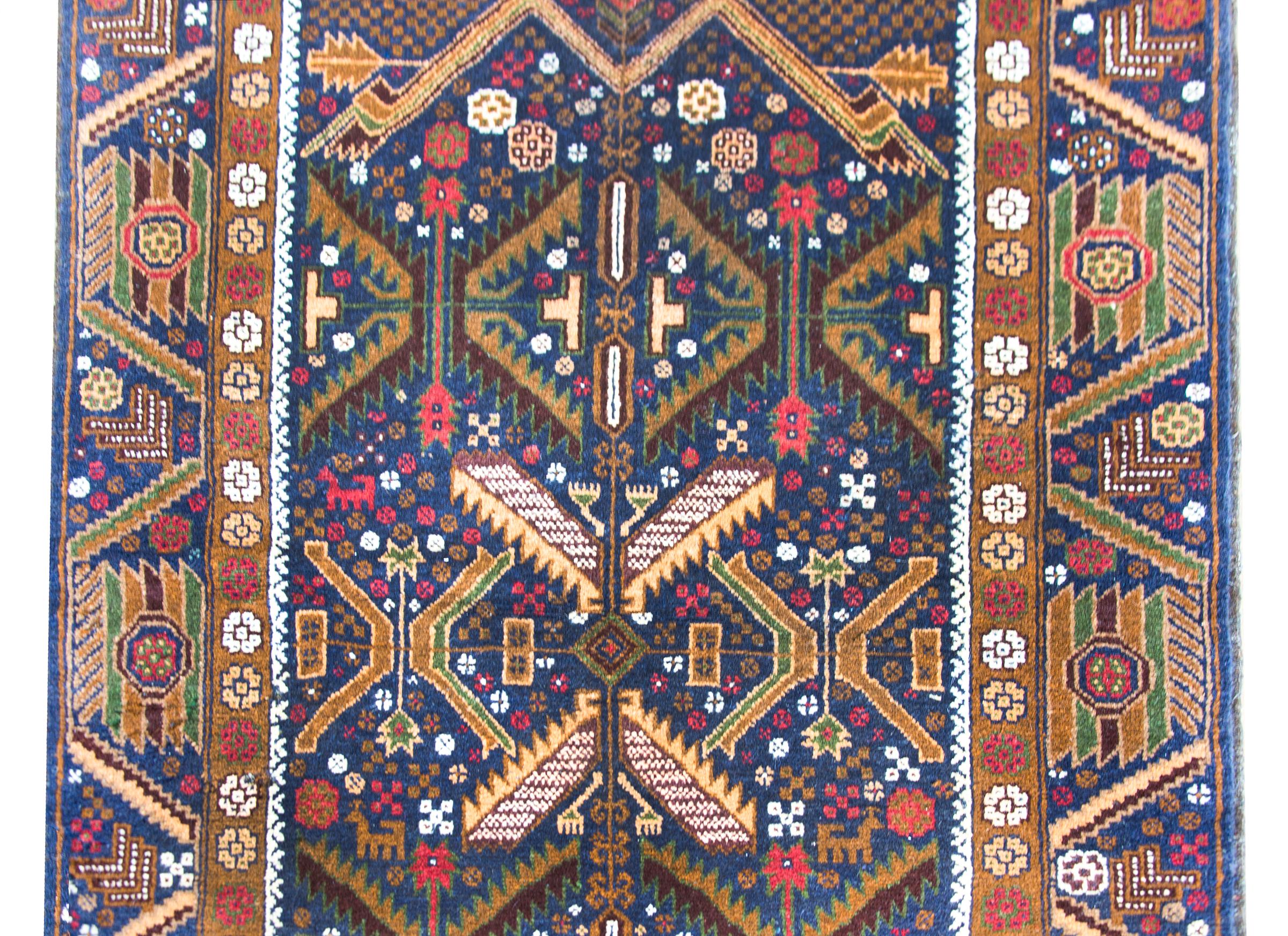 A wonderful vintage Afghani Baluch rug with a fantastic geometric pattern with stylized leaves, flowers, and chickens, and goats, and all surrounded by a wide border with more stylized flowers and leaves.