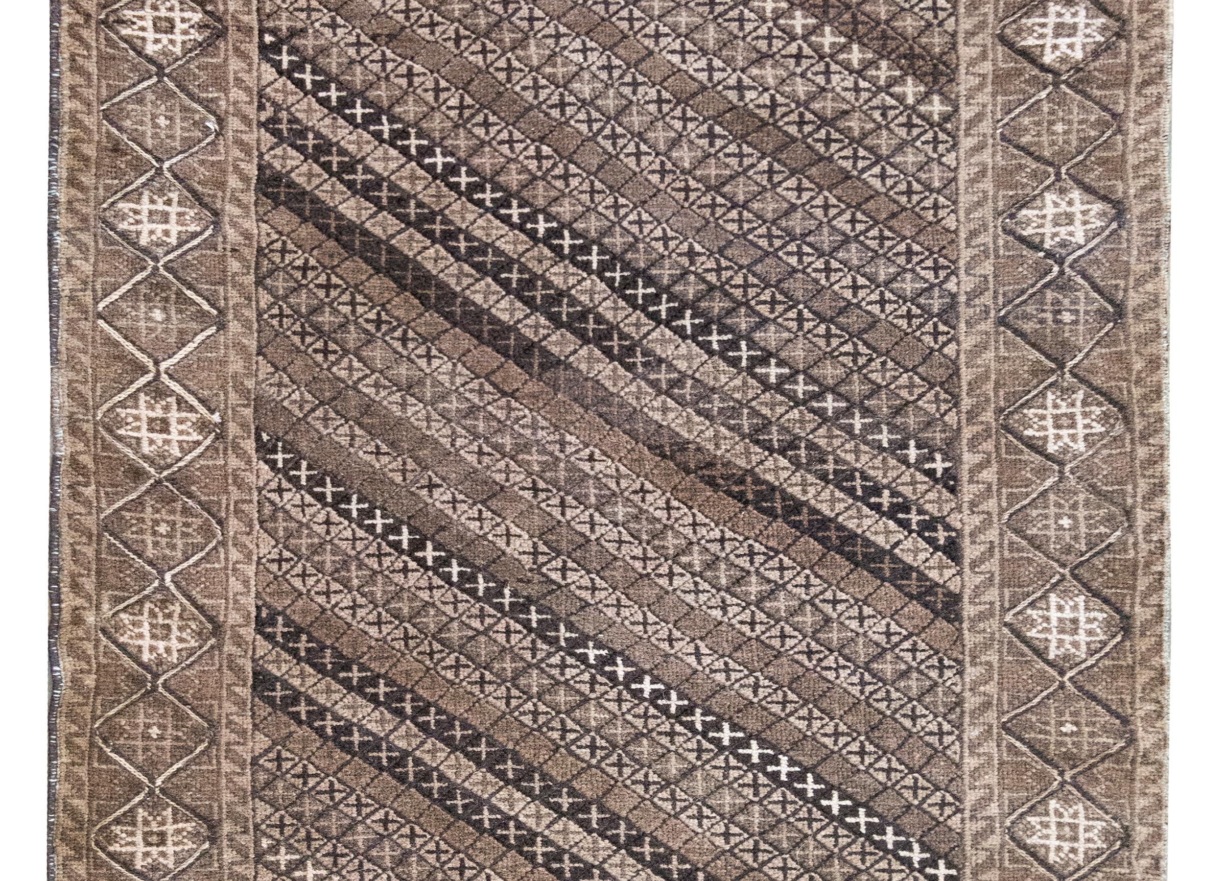 A wonderful late 20th Century Persian Afghani Balch rug with a central field composed with a diagonal striped pattern created from myriad diamonds with crosses in the center, surrounded by a repeated stylized floral patterned border, and all woven