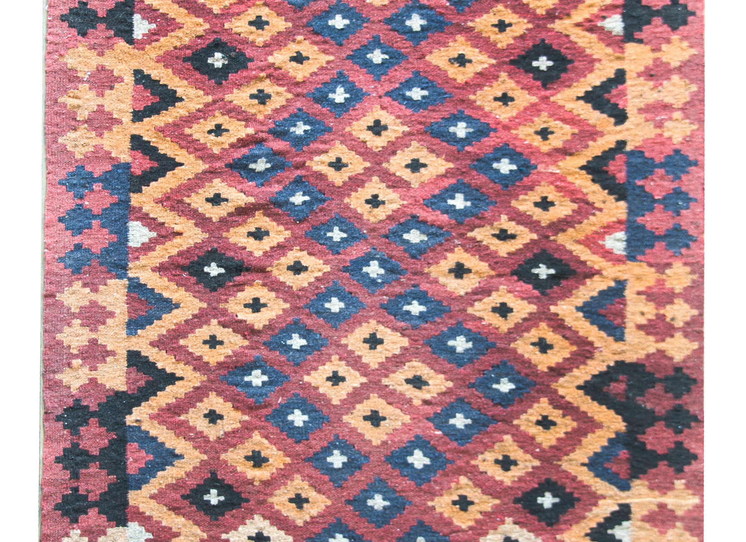 A wonderful mid-20th century Persian Afghani Kilim with an all over diamond pattern woven with an indigo diamond zigzag pattern against a golden diamond field. The top and bottom borders contain multicolored stripes and the sides borders contain