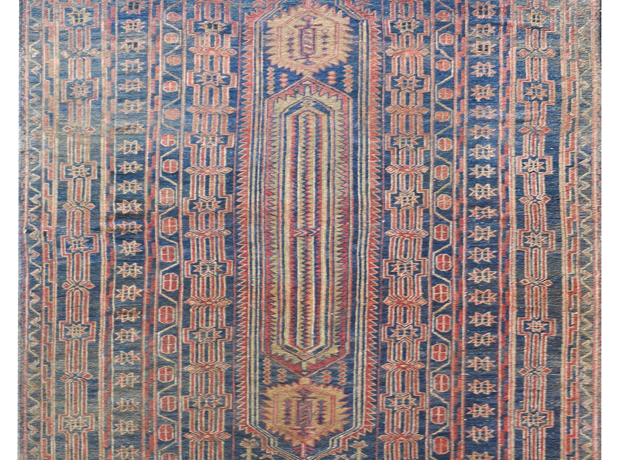 An incredible late 20th century Afghani Bashir flatweave rug with tribal pattern woven with stylized flowers and vines woven in crimson, indigo, and undyed wool.