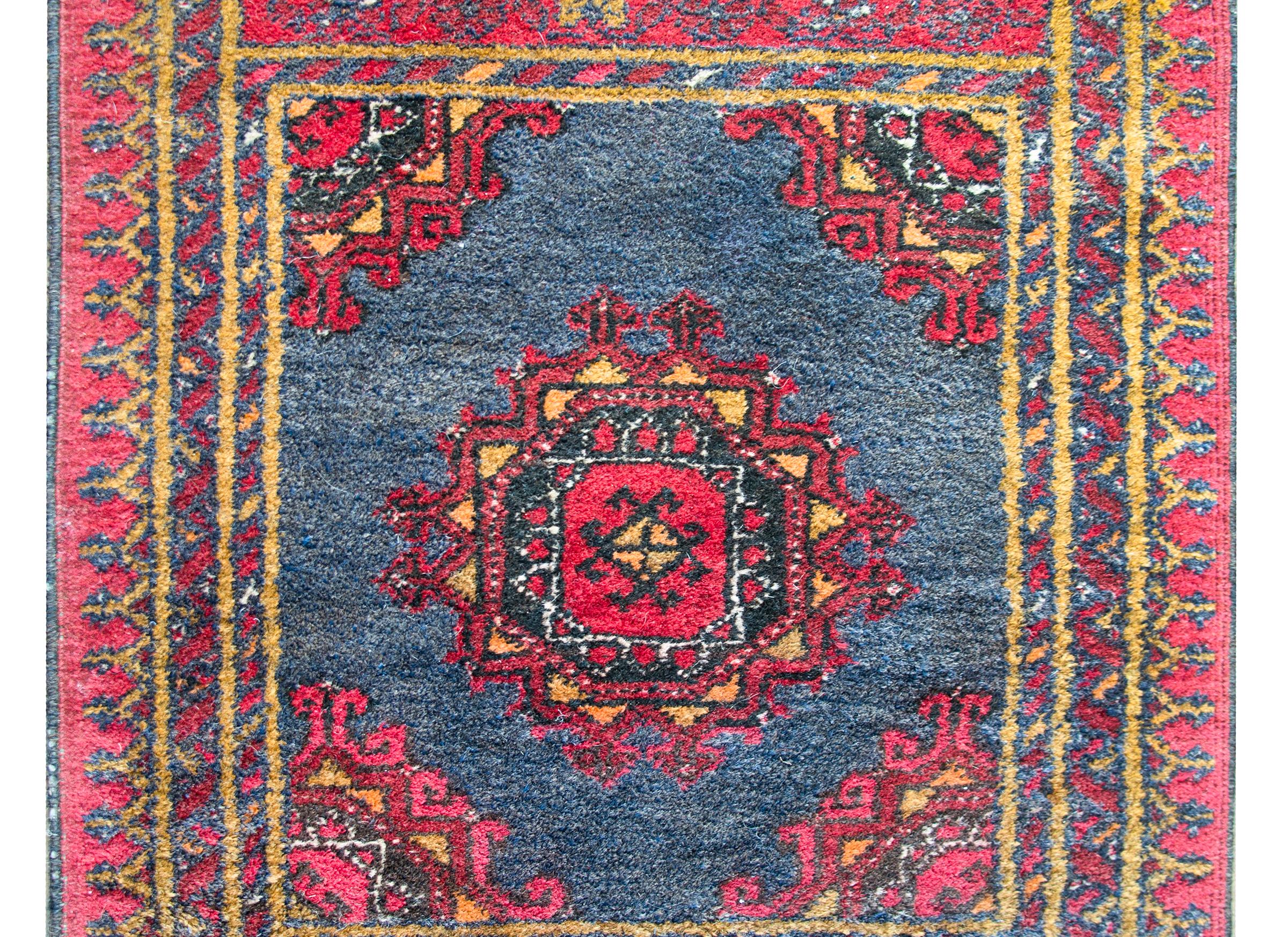 A beautiful vintage Afghani Bashir rug with a central geometric and stylized floral medallion woven in crimson, black, white, and gold, set against a gray background, and surrounded by a complex border containing myriad petite geometric patterned