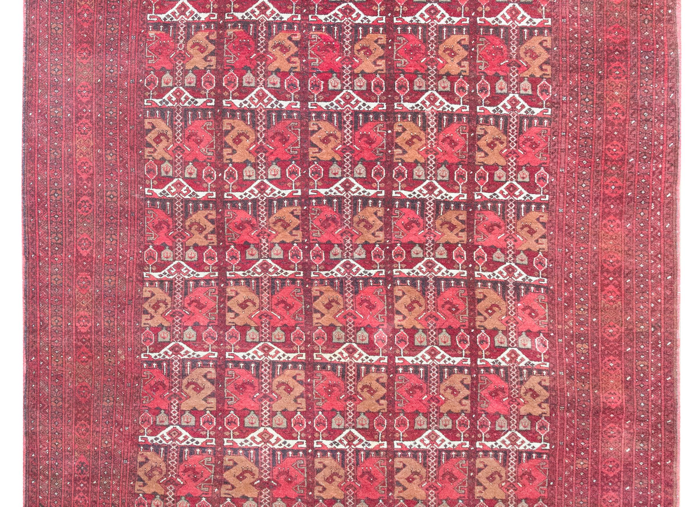 This vintage late 20th-century Afghani Bashri rug is a striking example of tribal textile artistry, woven in rich tones of crimson, brown, coral, white, and tan wool. The field features an allover pattern of stylized paisleys—ancient motifs