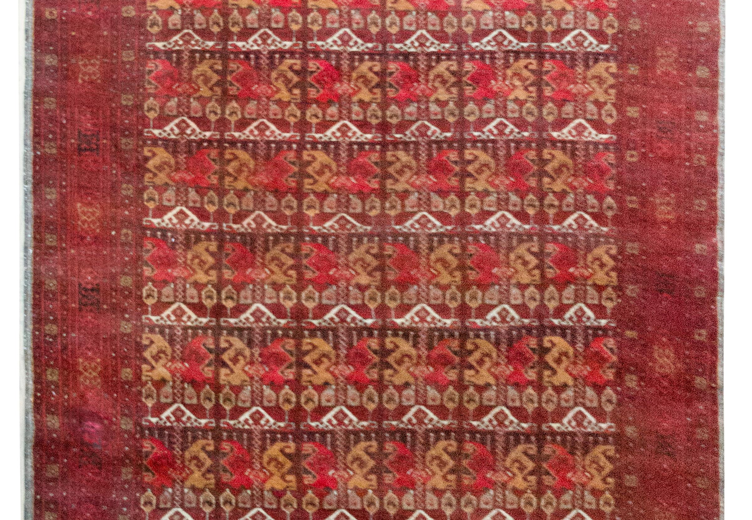 Ce tapis Bashir afghan vintage de la fin du 20e siècle est une pièce maîtresse, nouée à la main avec de la laine riche dans les tons cramoisi profond, ocre doré, ivoire et marron foncé. Son champ présente une répétition à grande échelle de motifs
