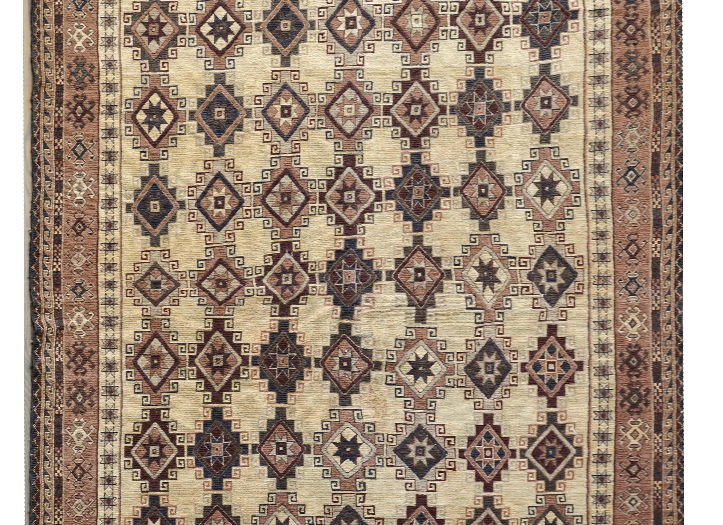 A wonderful vintage Afghani Sumack rug with an all-over diamond pattern woven in muted reds, indigos, pinks, and creams, and surrounded by a wide border with a wonderful stylized floral pattern woven in similar colors as the field.