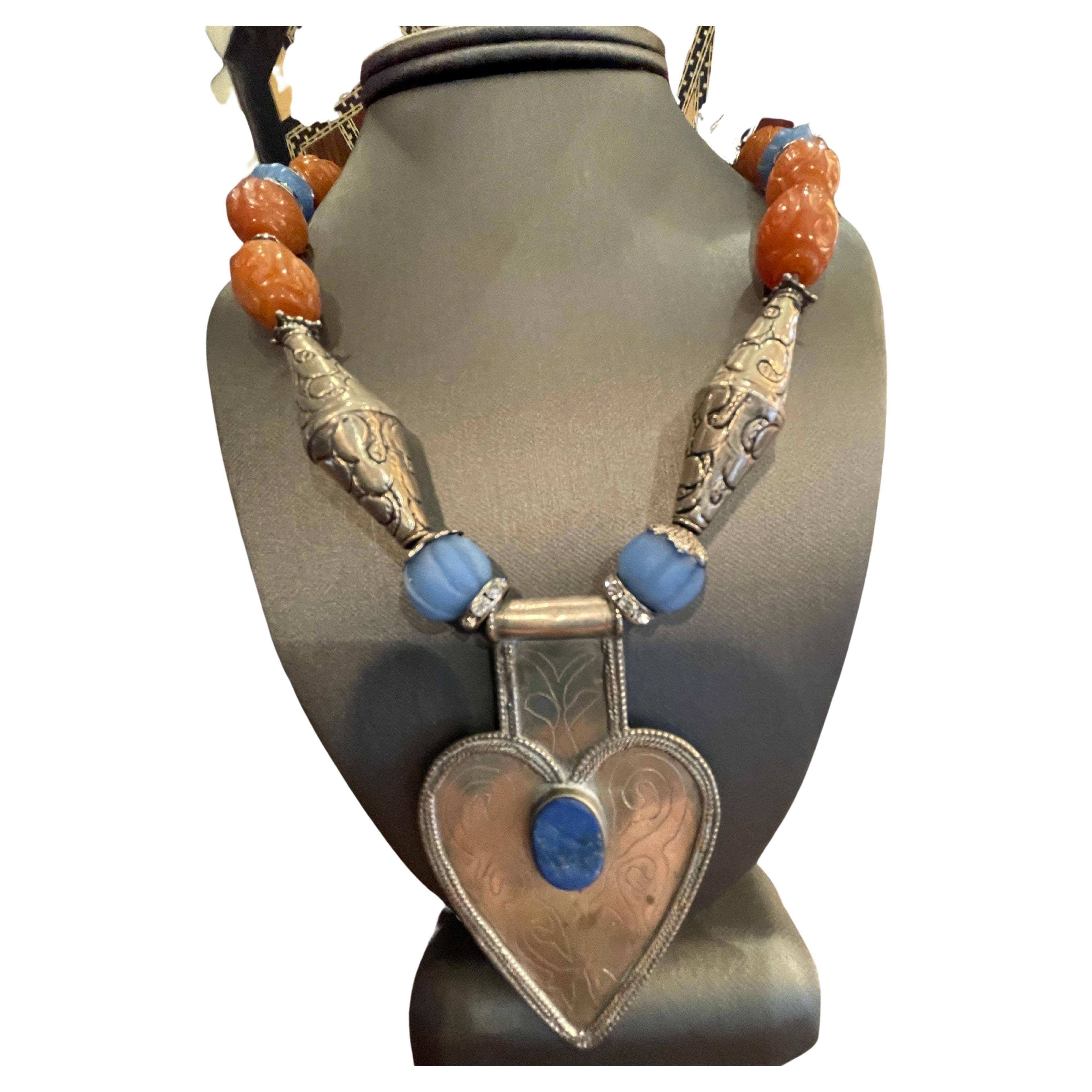 Vintage silver and lapis lazuli Afghani pendant necklace is on offer from LB. This fabulous heart shaped pendant is strung on a string of carved antique,Chinese,carnelian beads,melon shaped antique Tibetan blue glass beads,Tibetan silver chased