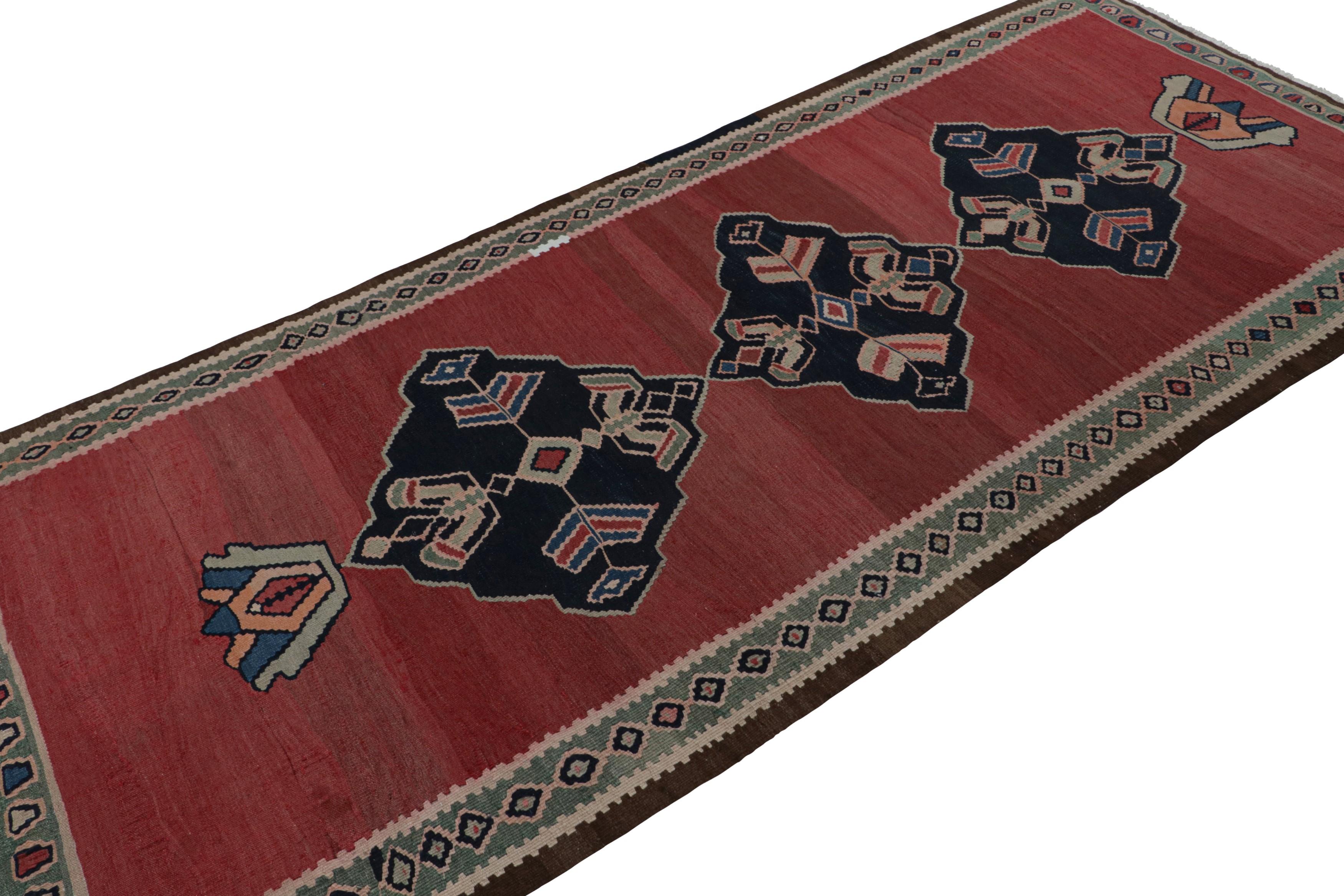 Handwoven in wool, circa 1950-1960, this 4x9 Afghani tribal Kilim rug, features an open red field and midnight blue medallions, along with several bright, playful colors but especially present pink and bright green notes.  

On the design: 

A