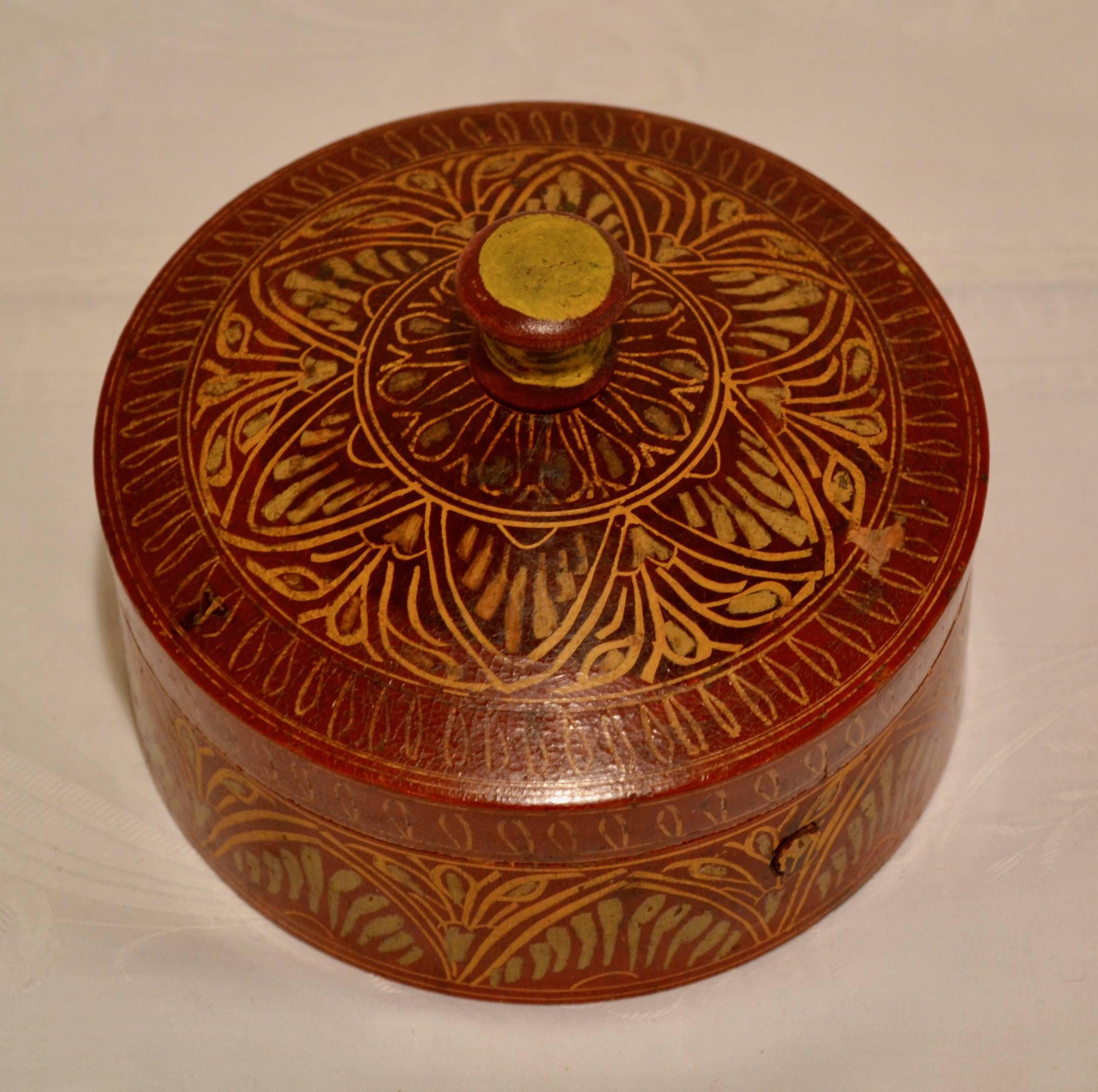 This is a vintage hand-turned, hand-painted tribal wooden spice box from Afghanistan with a stylized floral and leaf design in red, gold, and yellow. It is in superb condition with a well-fitting lid and only a few chips to the paint to testify to