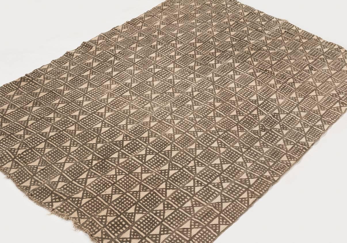 This light brown mud cloth was made circa 1980s and was made from handwoven strips of cotton, stitched together. Mud cloth (also known as Bògòlanfini or bogolan) is a handmade Malian cotton fabric traditionally dyed with fermented mud. This mud