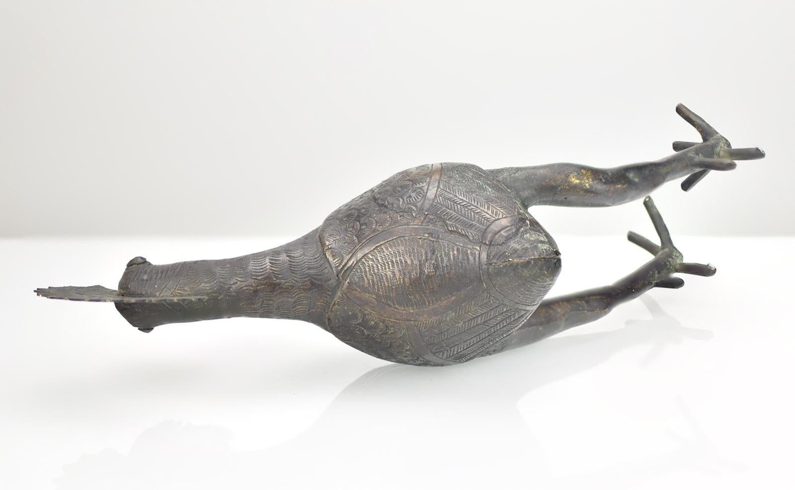 Cette étonnante sculpture de coq en bronze est un bel exemple de l'art tribal africain, originaire des régions culturelles d'Ife et du Bénin au Nigeria. Réalisée dans un style folklorique primitif, cette figurine présente des détails complexes sur