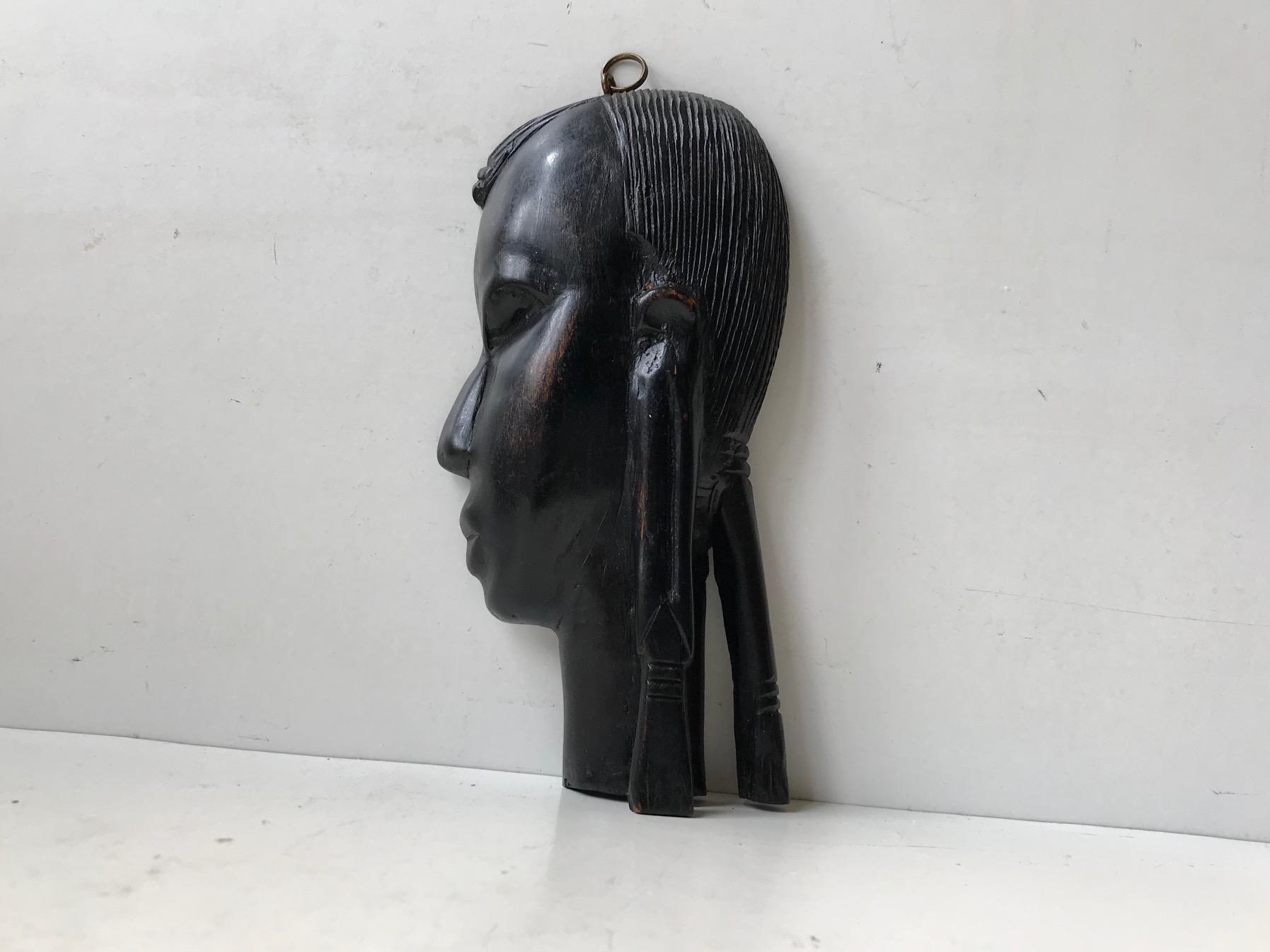 African wall plaque depicting a warrior in profile. It is made from dense/heavy ebony by a trained artisan probably in Lagos circa 1960-70. It is wall hung via a brass loop. It has no markings. Measurements: H: 21, W: 10 cm.