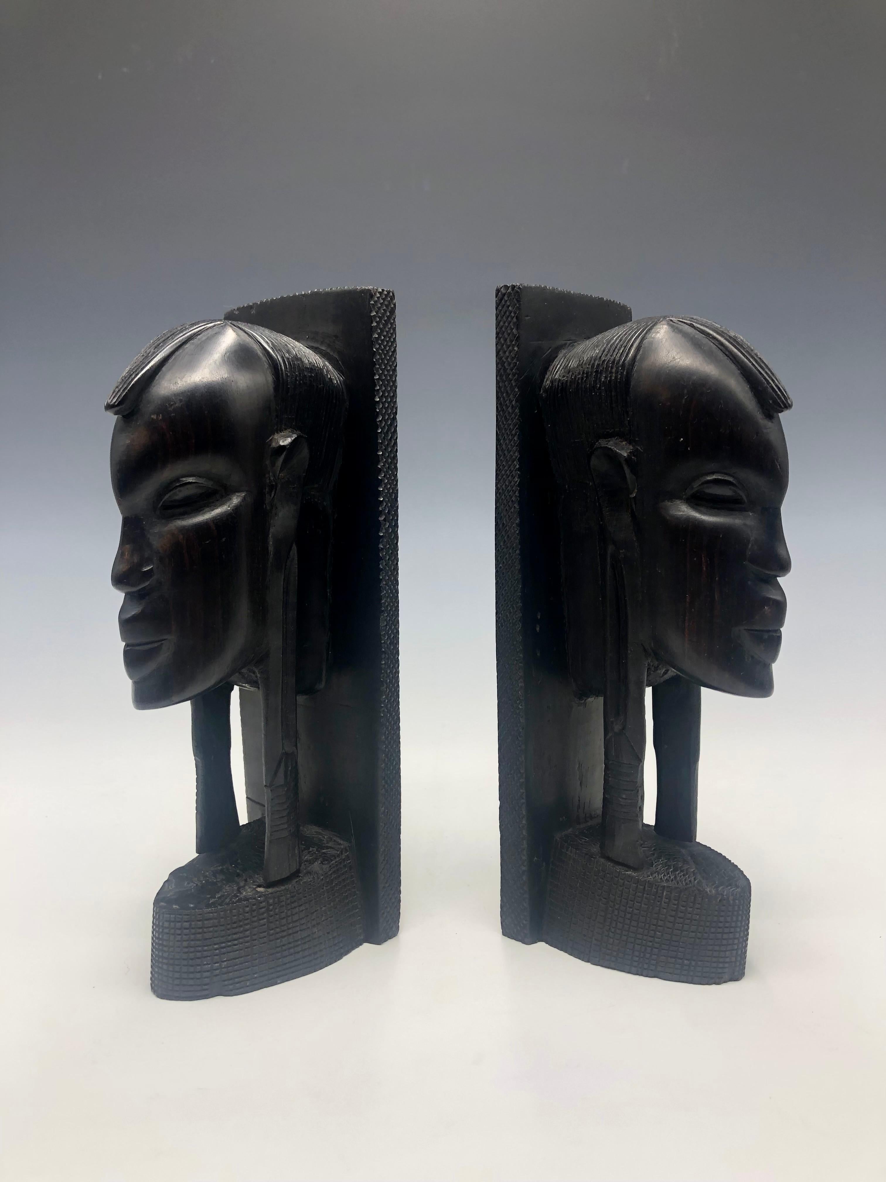 Add a touch of Africa to your bookshelf with these vintage ebony figurative bust bookends. These bookends are hand carved from hardwood ebony and feature intricate tribal patterns and detailed carvings. The deep black ebony color and wood-finished