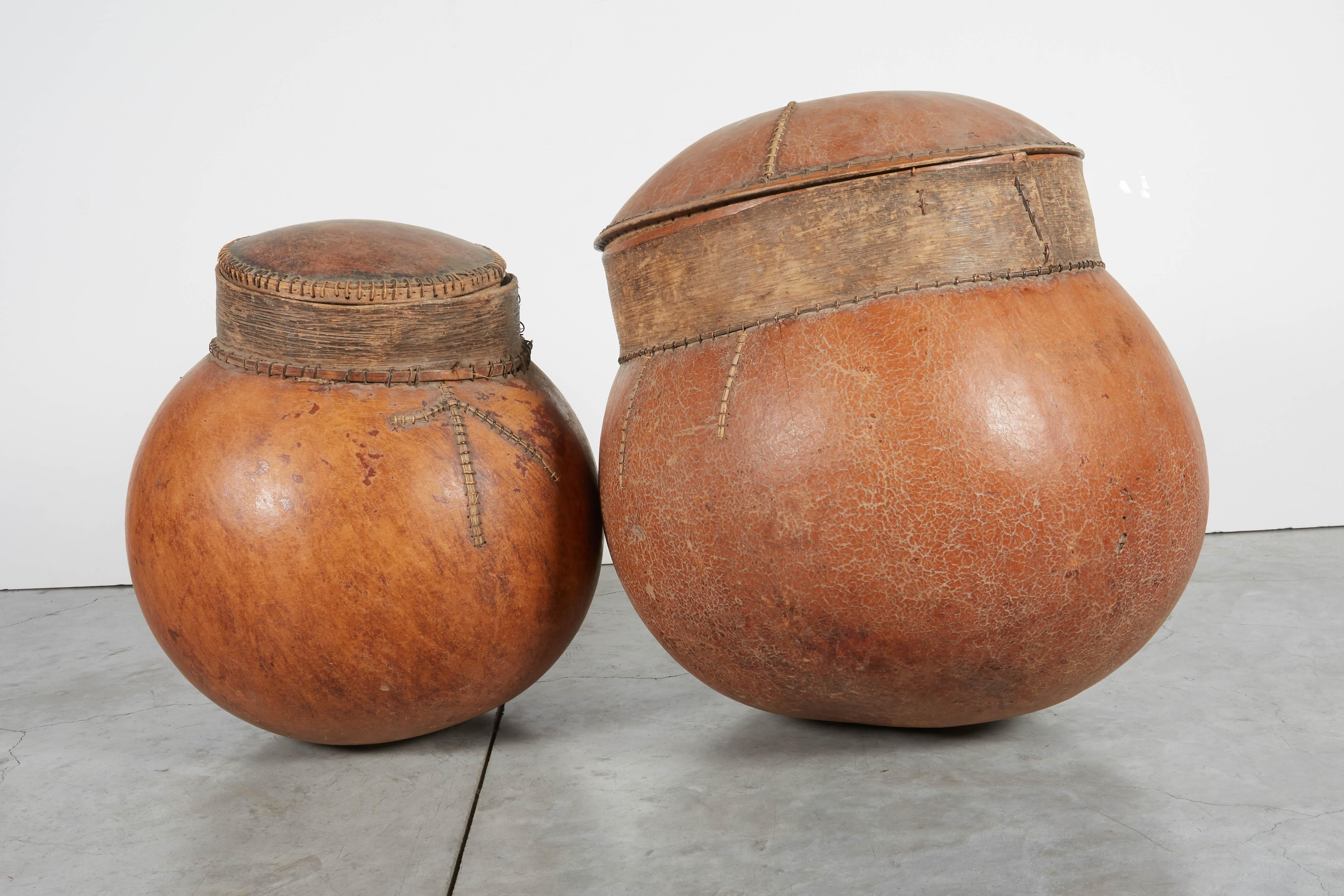 Two beautifully weathered African gourd storage vessels with fitted covers and old stitched repairs. Wonderful objects and great conversation pieces.
Sold individually.
Dimensions:
Large: Diameter 16 height 17; small: Diameter 15 height 15.