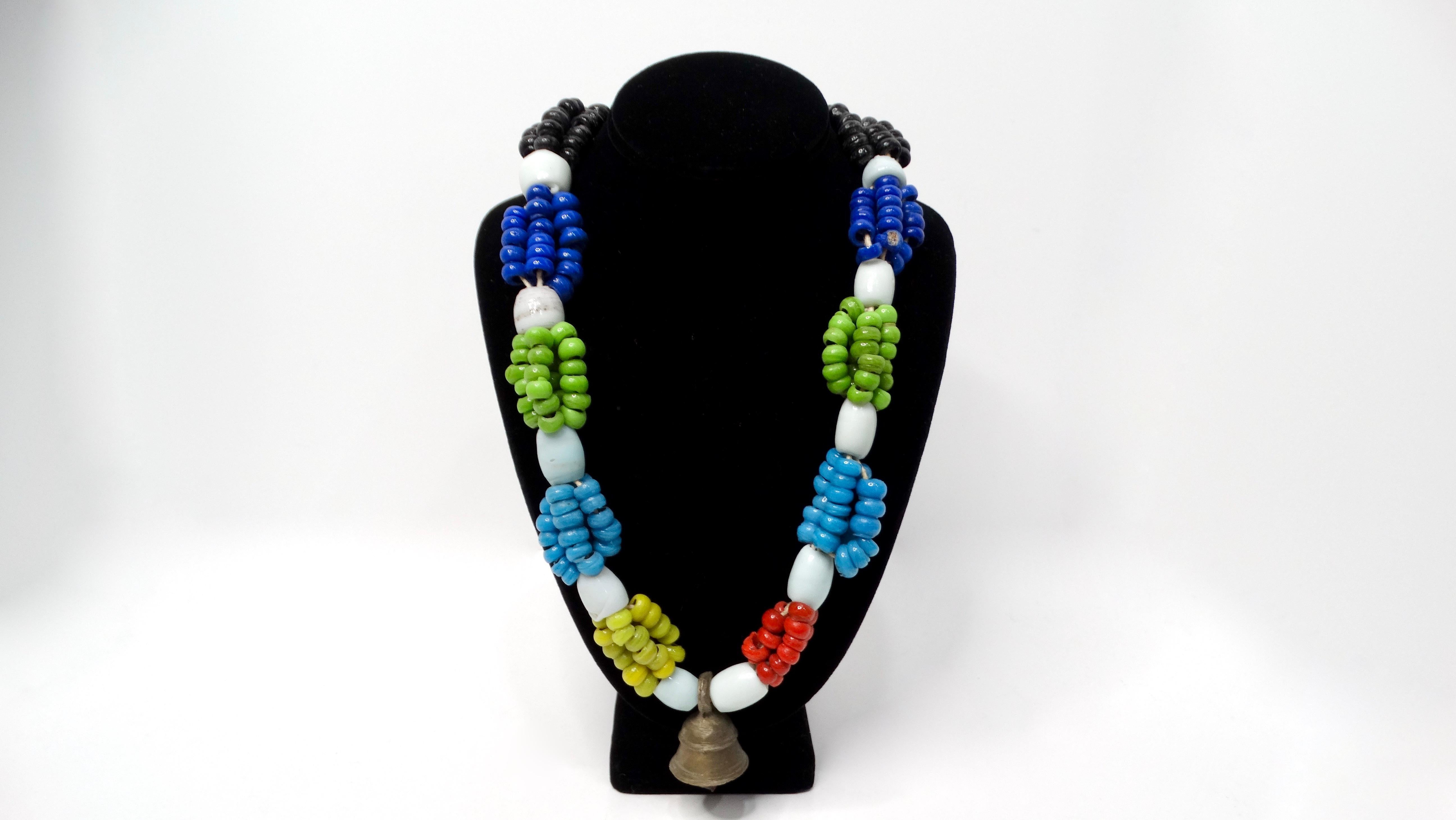 The Vintage African Tribal Multicolor Glass Beaded Necklace with Bell is a vibrant celebration of cultural heritage and artisanal craftsmanship. This striking necklace features clusters of assorted colored glass beads, expertly combined to create a