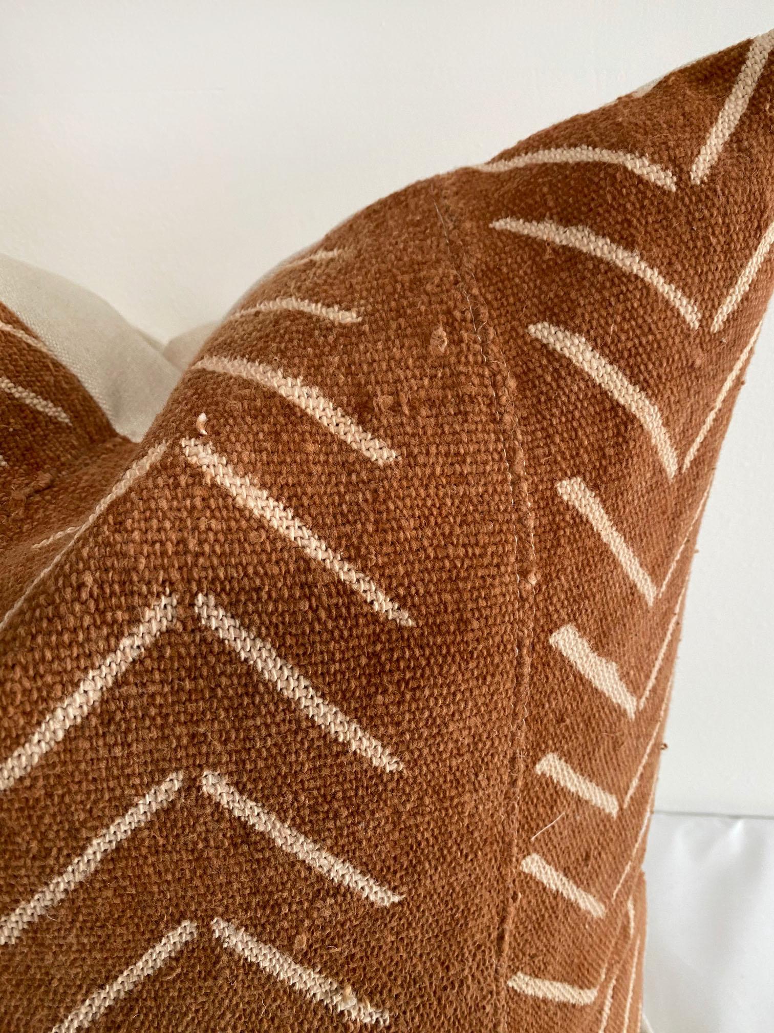 Vintage African Mudcloth pillows, deep burnt orange rust color, with off white arrow pattern. Sewn with a zipper closure, and natural linen backing. The inside has an overlocked edge, can be machine washed on gentle. For color fading dry clean is