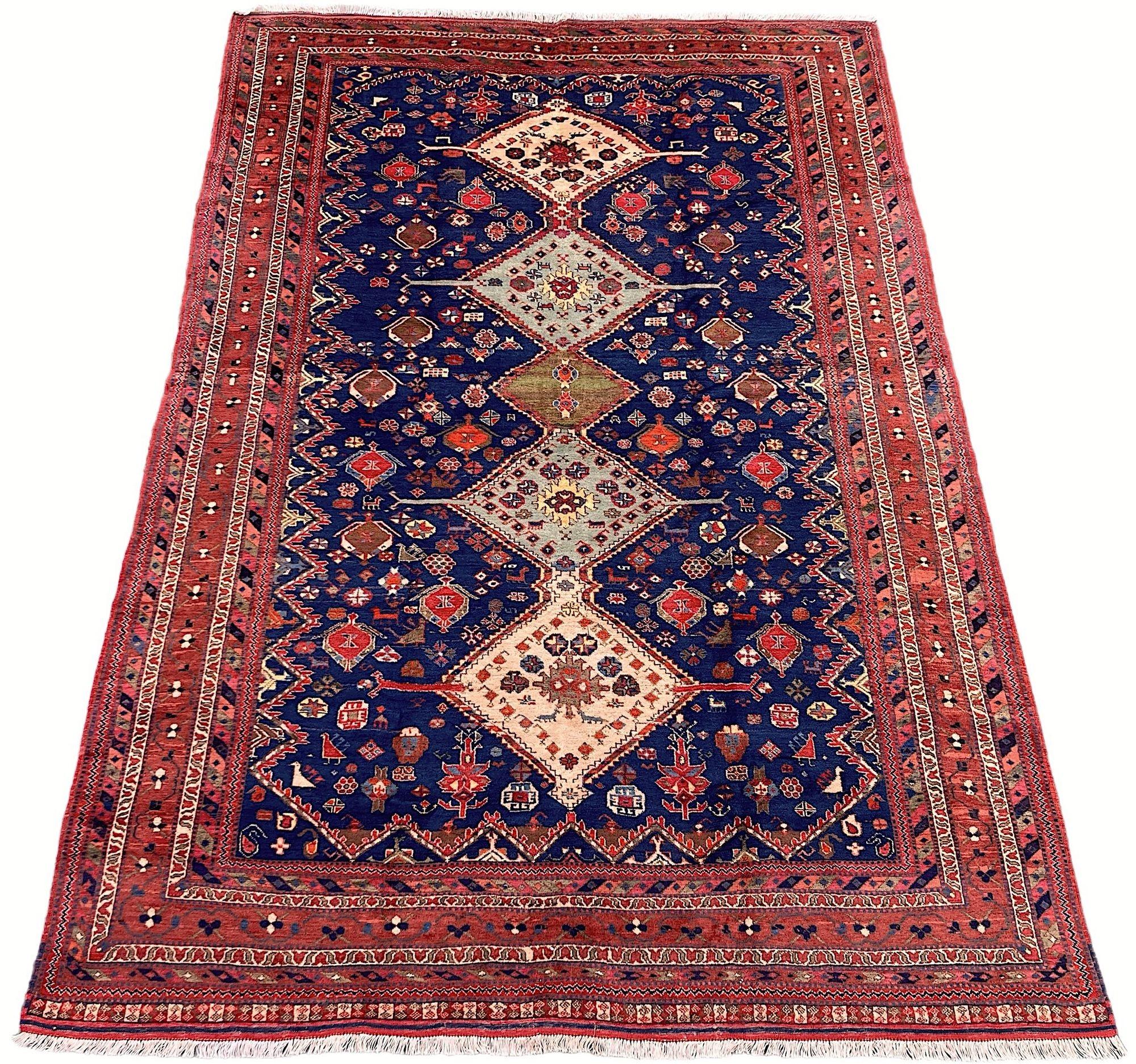 A lovely vintage Afshar carpet, hand woven circa 1940. The design features 5 geometrical medallions on a rich indigo field of stylised flowers and figures surrounded by an intimate terracotta border. Finely woven with soft, velvety wool and some