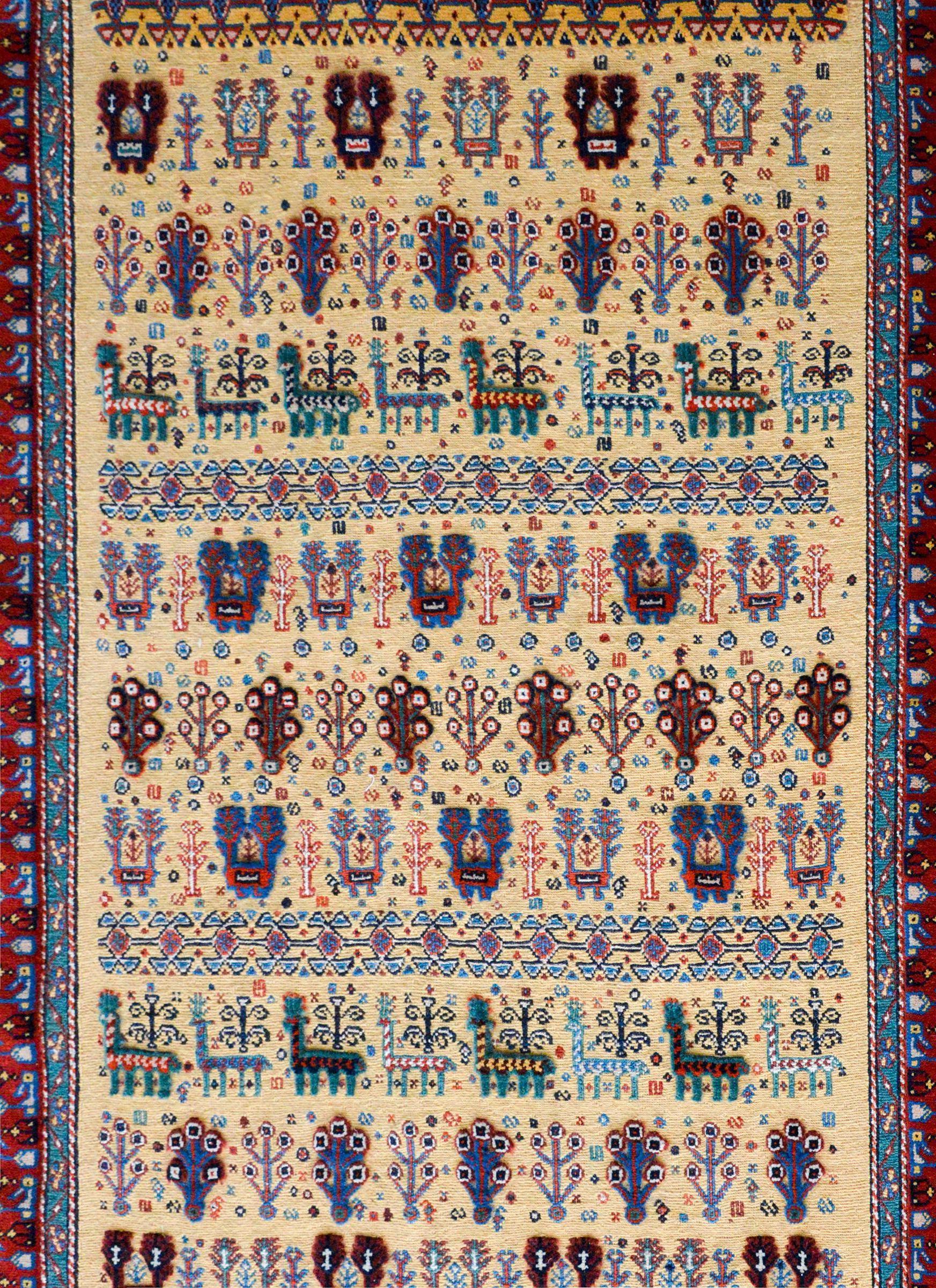 An incredible vintage late 20th-century Afshar rug with a pattern with alternating trees-of-life, deer, and stylized floral patterns all woven in cut pile set against a yellow flat weave background. The border is striking with several stylized