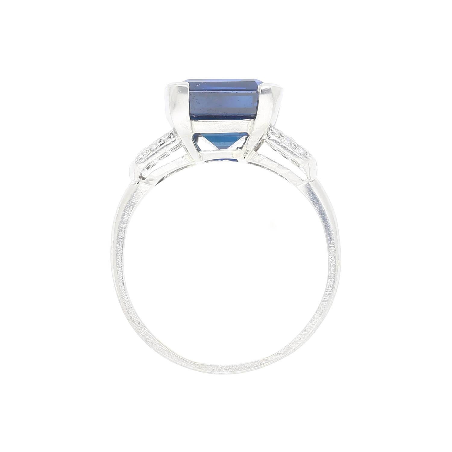 This platinum ring features a 6.80 carat AGL certified Emerald cut Blue Sapphire of Thai origin with no heat treatment, as well as 6 baguette cut diamonds and 12 round cut diamonds. The vintage setting beautifully highlights the sapphire's