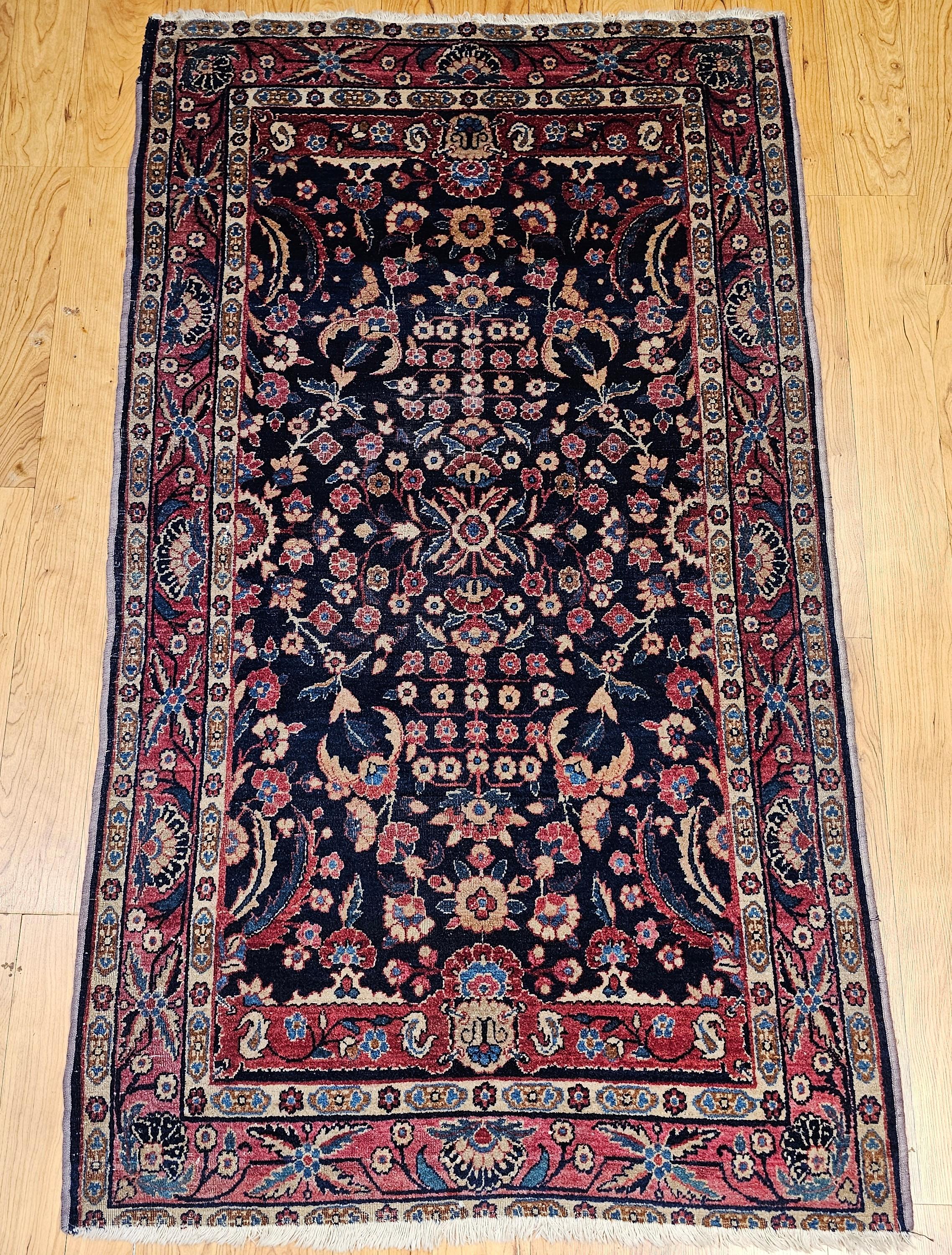 Tappeto vintage indiano Agra con motivo floreale allover nei colori blu navy e rosso dei primi anni del 1900.   Questo tappeto antico di Agra presenta il tradizionale design Mughal dei tappeti tessuti nel XVI secolo in India. Il campo presenta bande