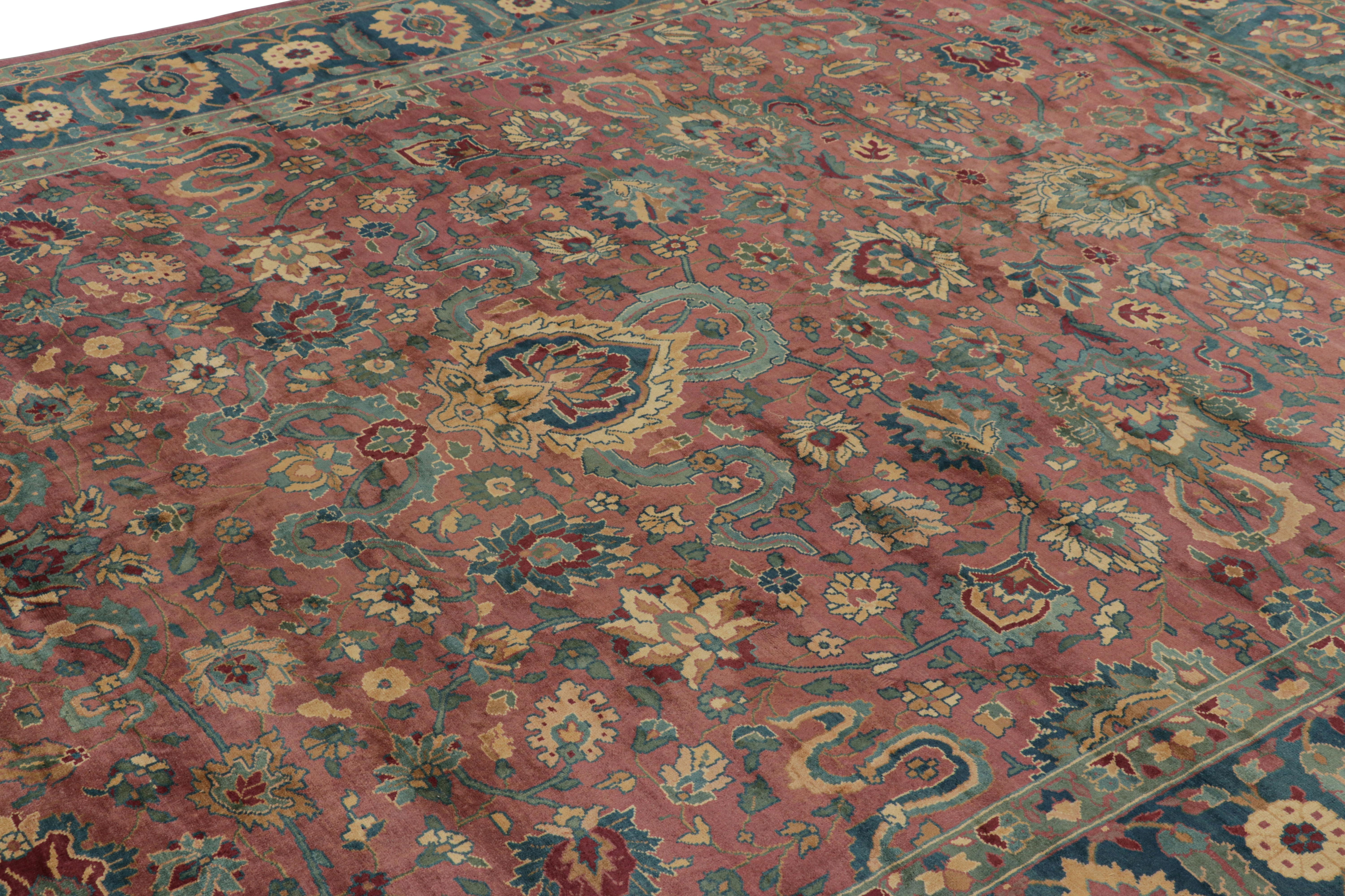 Annodato a mano in lana e proveniente dall'India intorno al 1950-1960, questo tappeto vintage 9x11 di Agra, caratterizzato da fitti motivi floreali in colori unici su un ricco campo rosso con bordo blu verde acqua, è una nuova curatela speciale di