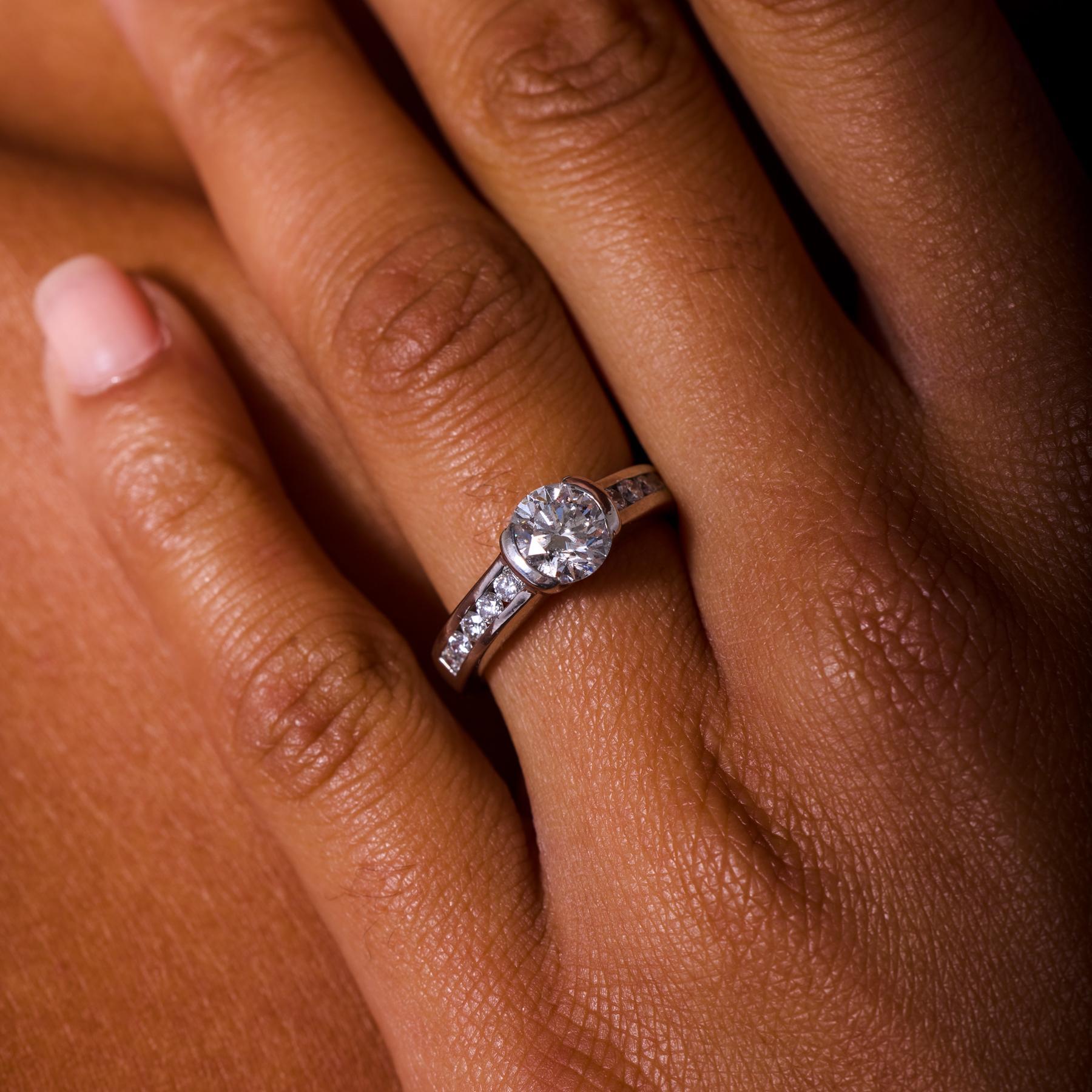 Senza tempo e radioso, questo anello di fidanzamento vintage sfoggia un diamante rotondo taglio brillante da 1,50 carati certificato AIG che brilla con un fuoco e una presenza accattivanti. Incorniciato da dieci scintillanti diamanti d'accento lungo