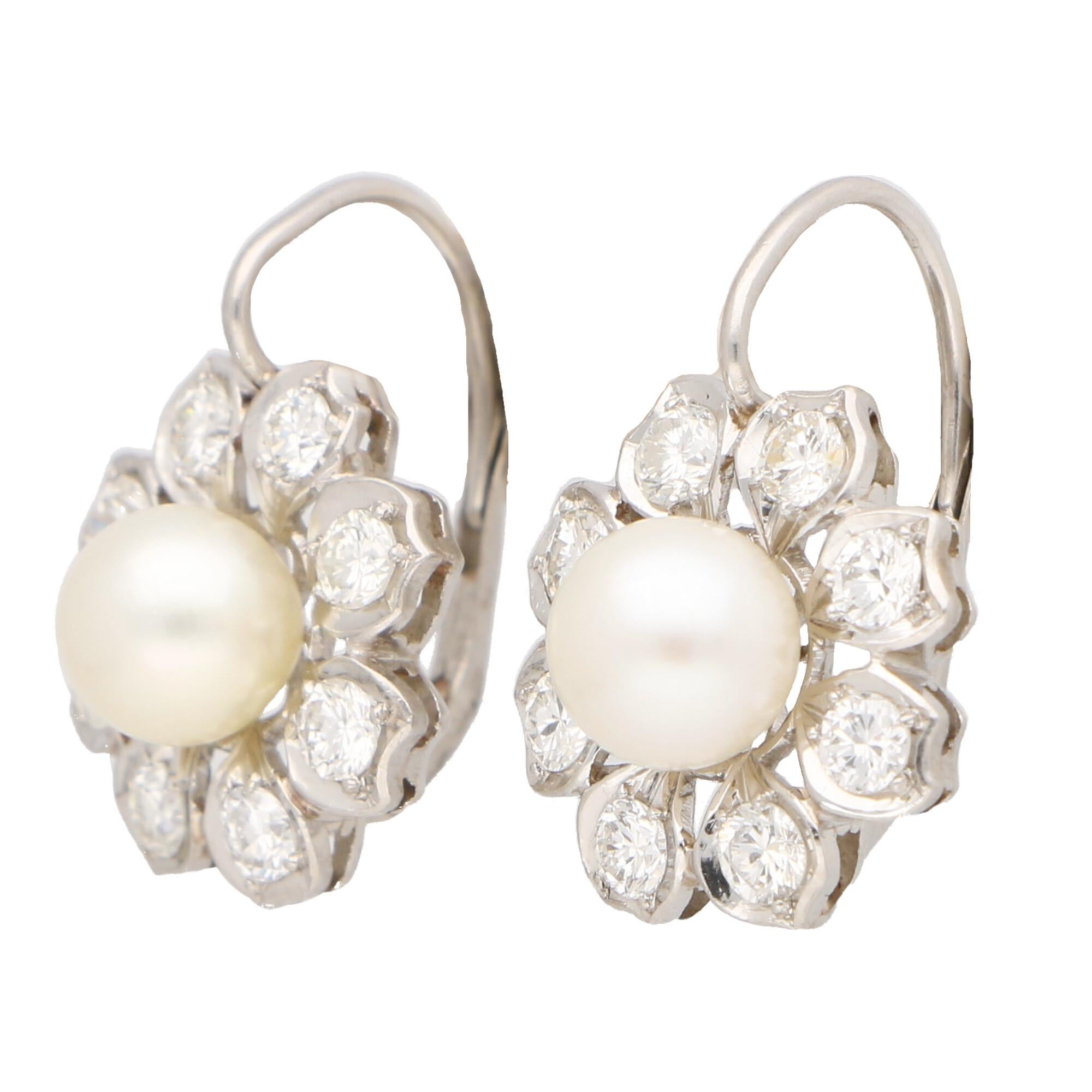 A beautiful pair of vintage Akoya pearl and diamond cluster floral drop earrings set in platinum.

Each earring is centrally set with a lovely 7 millimetre cream coloured Akoya pearl. This pearl is set within a beautiful platinum floral framework