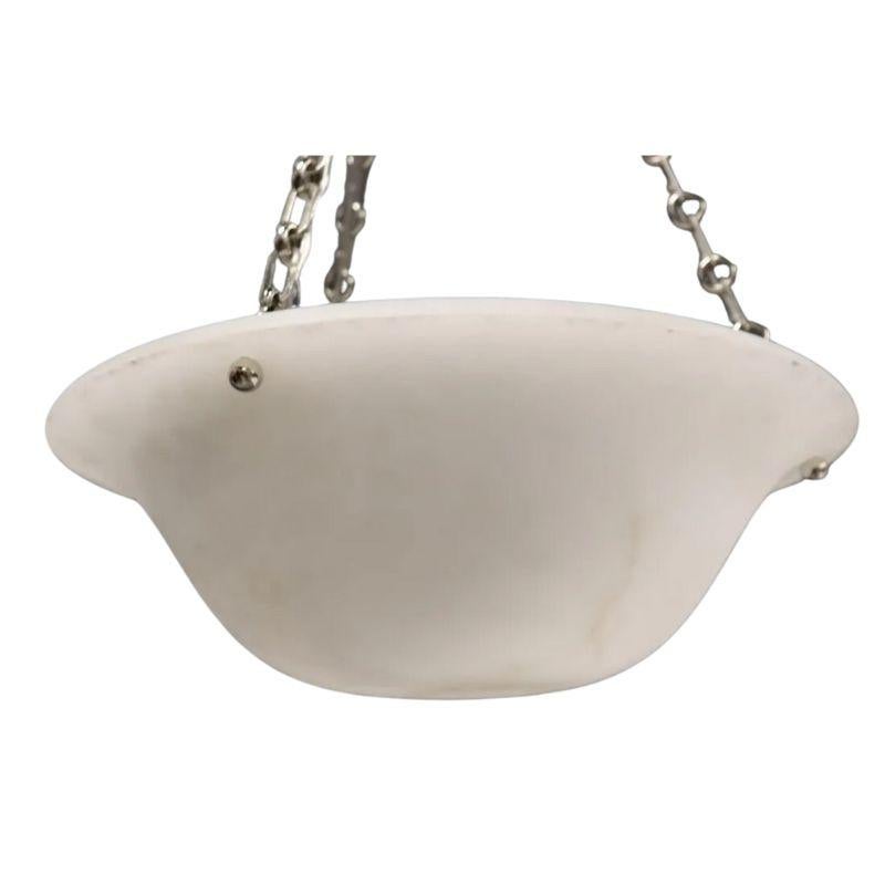 Una lampada a sospensione vintage a forma di piatto in alabastro con un profondo pozzo sul piatto.  Un design neoclassico con catena in nichel, montature a bottone e dettagli del baldacchino che evidenziano le leggere venature dell'alabastro.  Un