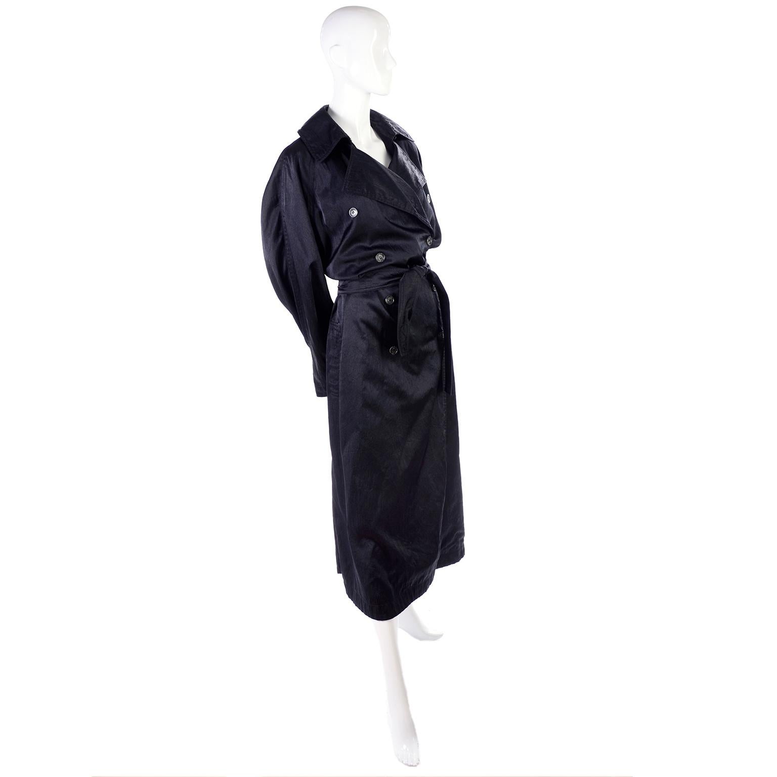 This is a great vintage Alaia long trench coat style raincoat with waist belt. This double breasted designer rain jacket has side slit pockets and can be worn buttoned all the way up, or with the lapels out. It has a pleated slit running up the back