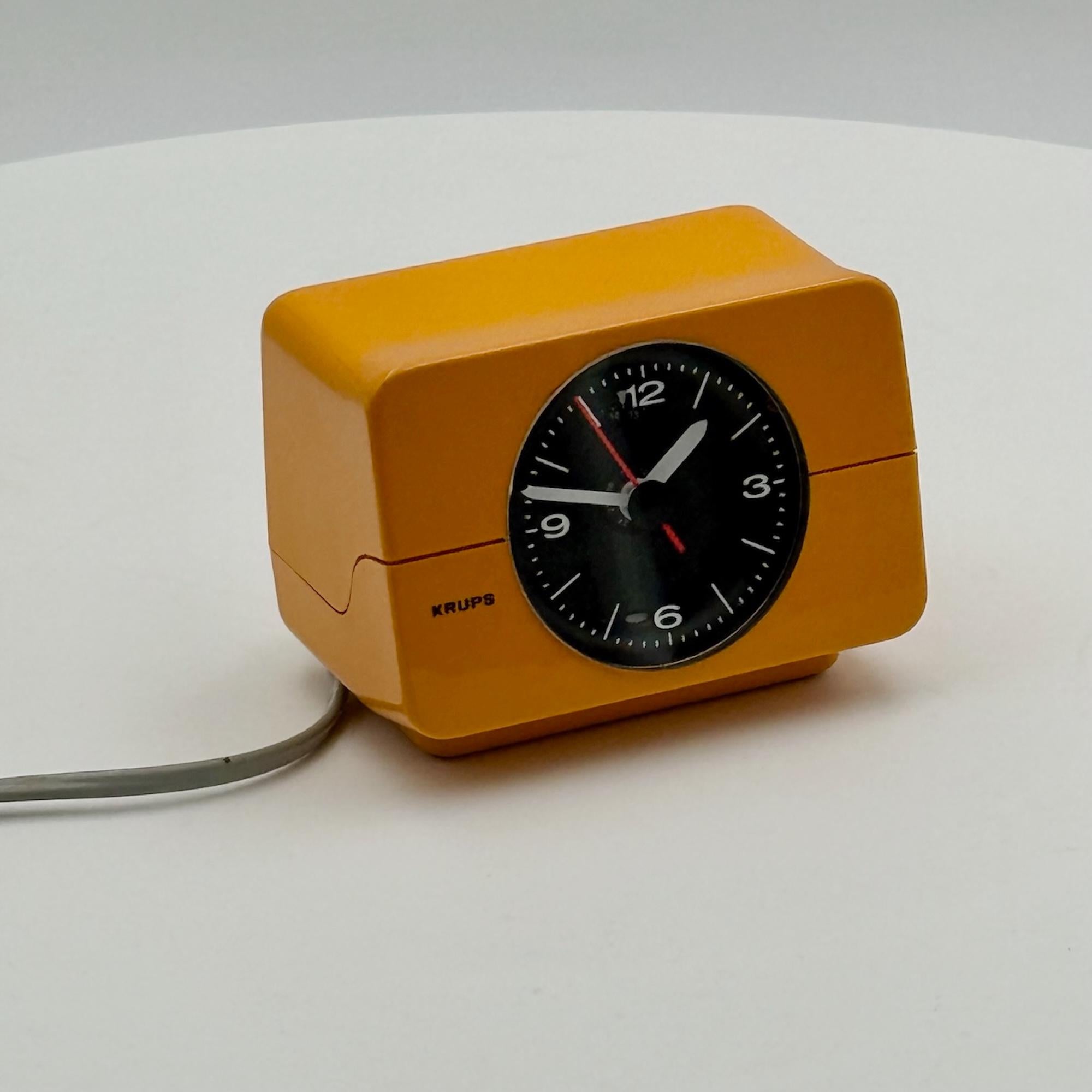 A definitive example of 1970s space age design, this Krups alarm clock showcases innovation and bold aesthetics. Crafted in West Germany, it features a mustard-yellow plastic casing with a contrasting black hand dial, epitomizing mid-century