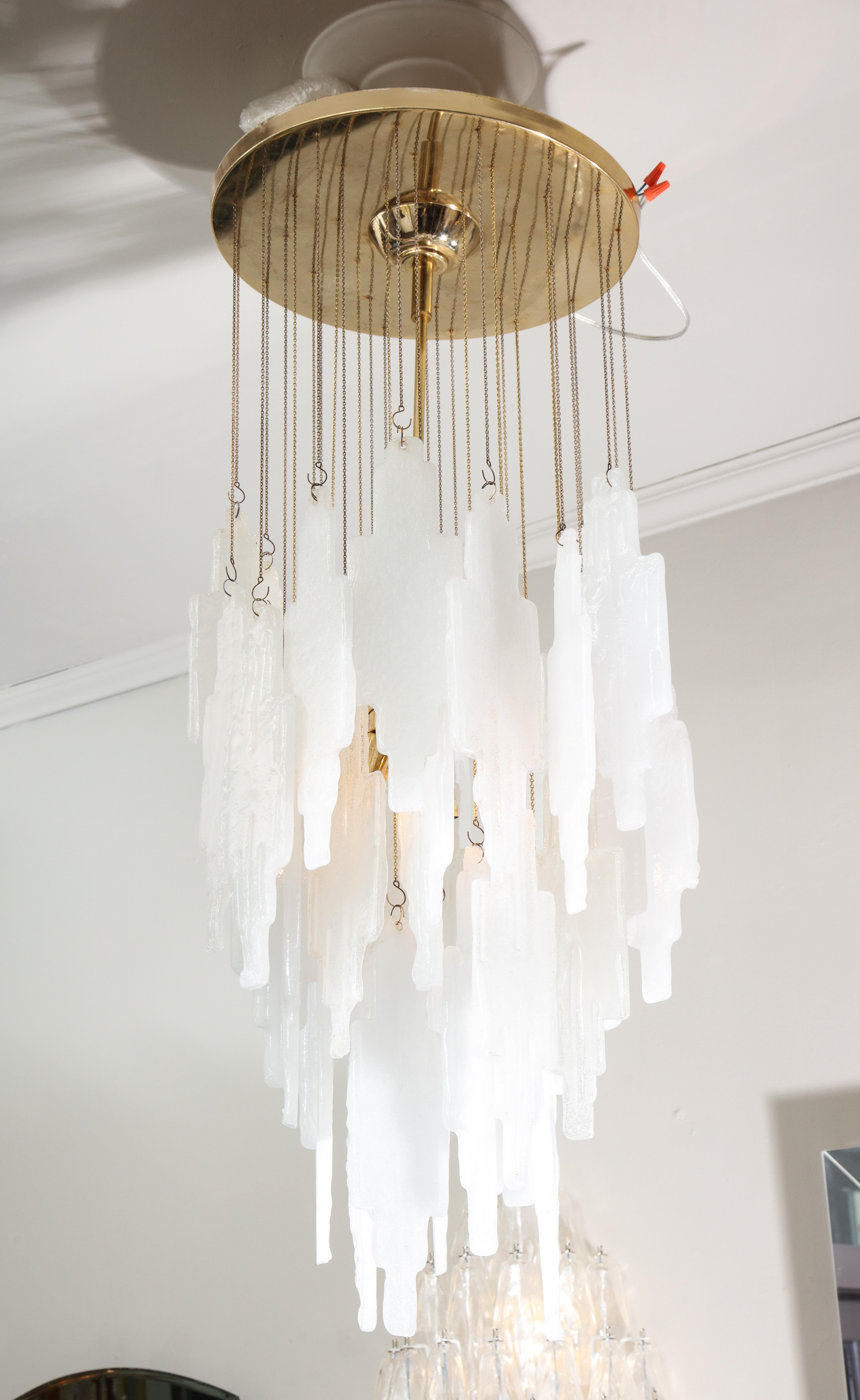 Unusual vintage lighting fixture with remarkable step-shaped crystal glass in clear and frosted color. Each glass is suspended elegantly by brass chain to create a beautiful cascading shape. The chandelier was designed and produced by Albano Poli