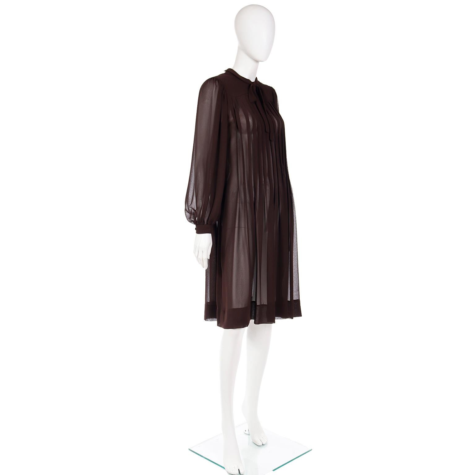This lovely vintage Albert Nipon brown pleated crepe dress is from the late 1970's. The dress is semi sheer and it can be worn over a slip or shapewear. The dress closes with fabric covered buttons and it has a tie at neck that can be knotted or