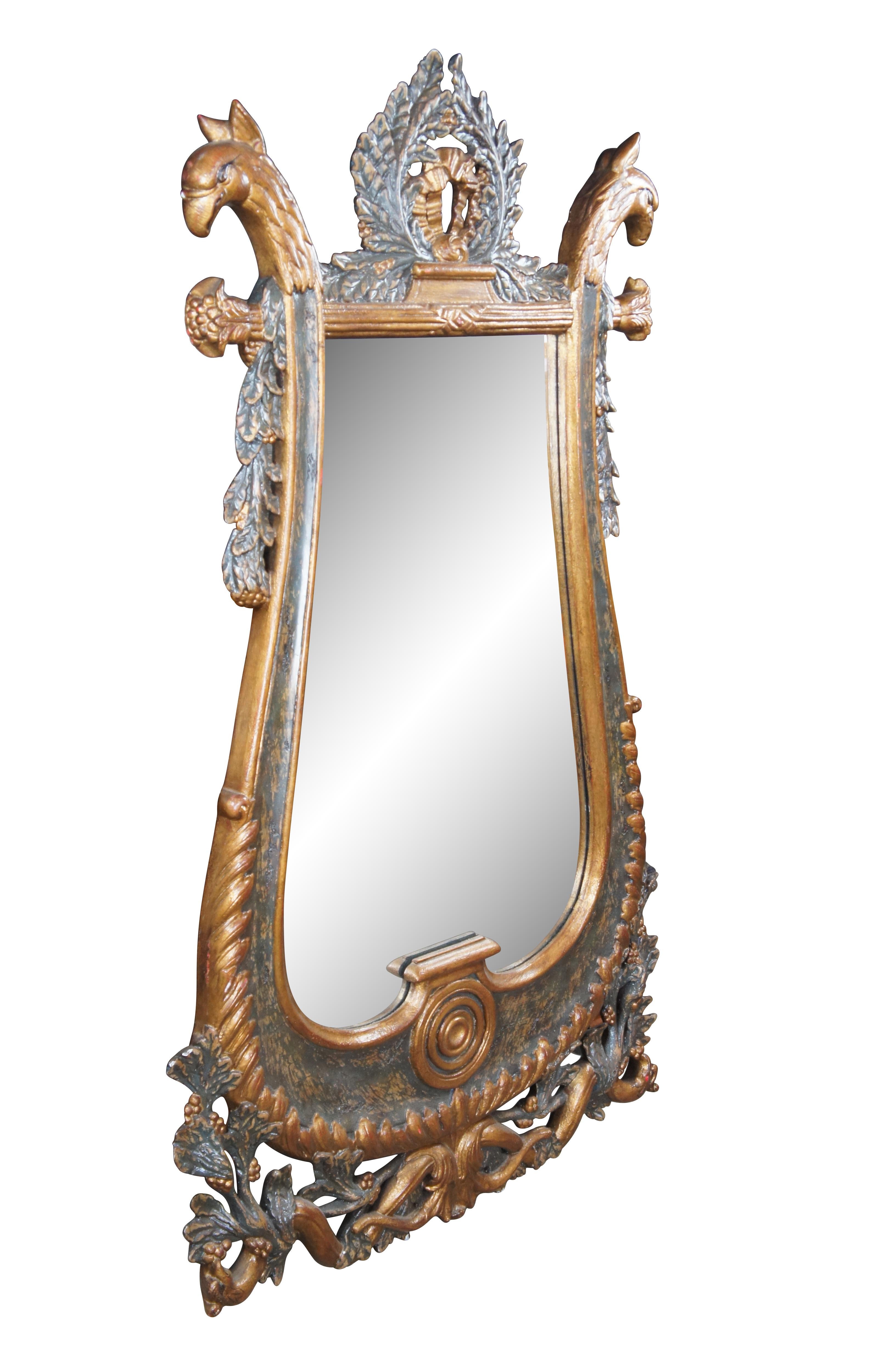 An elegant Louis XVI inspired wall hanging mirror by Alfonso Marina, circa late 20th century. Made from mahogany with ornate painted details.  Features a lyre shape with ornate central wreath flanked by figural griffon heads.   The body of the